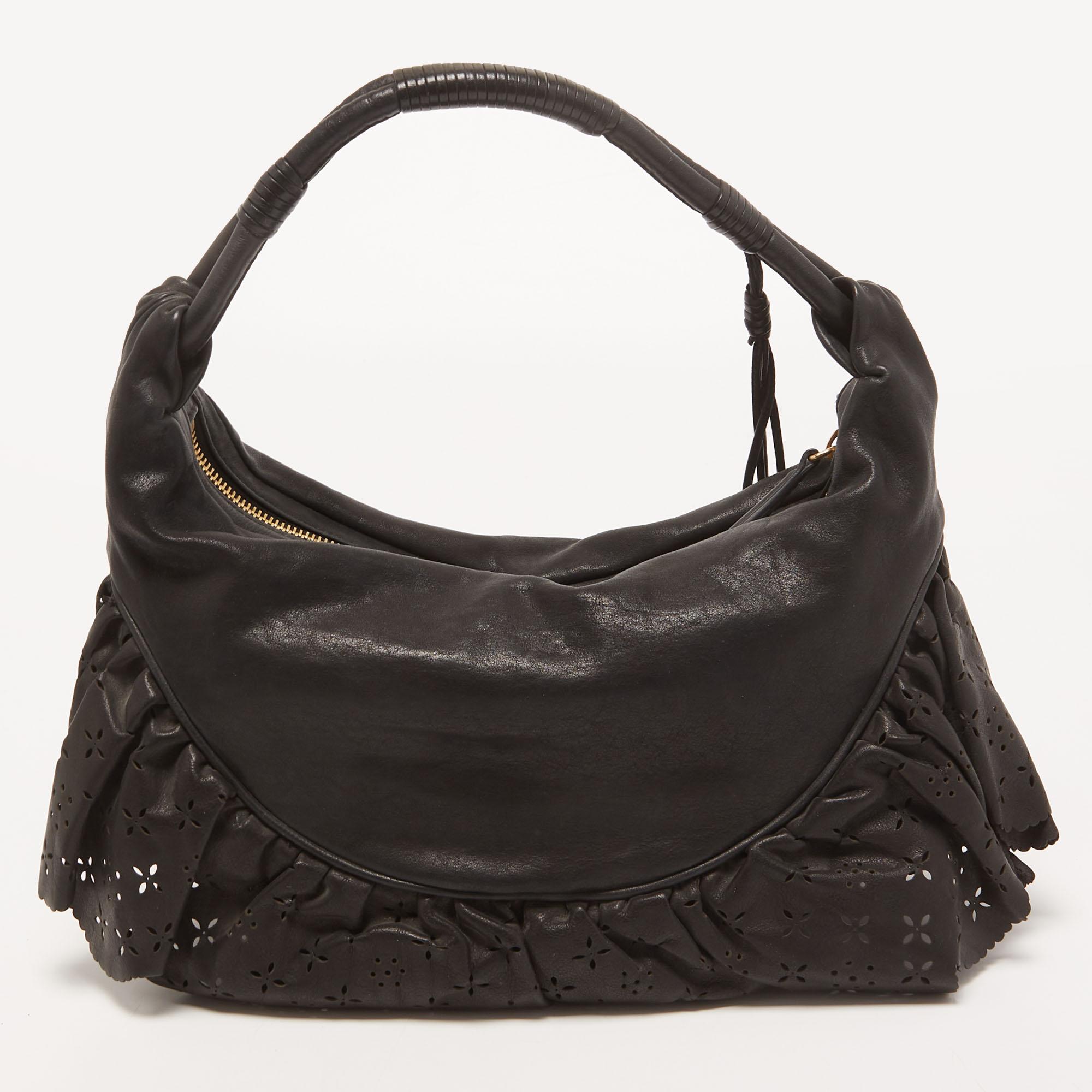 Charm your crowd with every swing of this Dior hobo. Crafted from leather, this black bag has lace-like ruffles and a top zipper which reveals a satin interior sized to carry your essentials. It is equipped with a top handle and styled with the