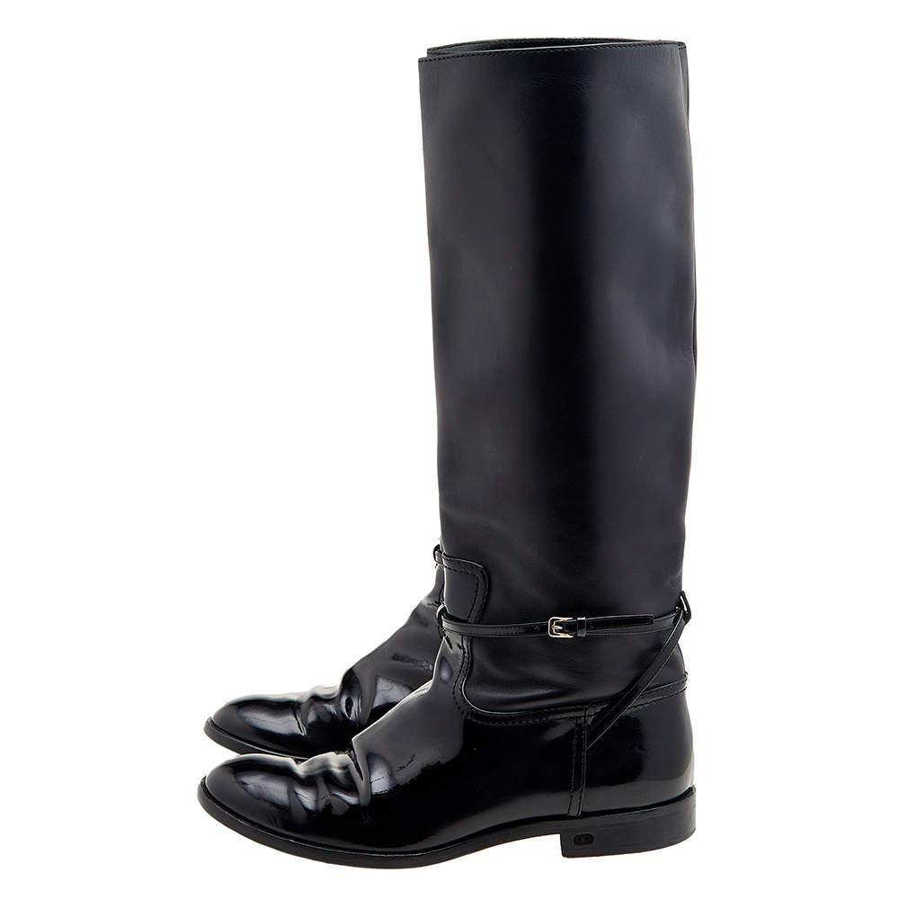 It's time to rock all your outings with these chic and smart boots from Dior that exude oodles of style. These black boots are crafted from patent and leather and flaunt round toes, leather lining, and low heels. They come with buckled straps. Pair