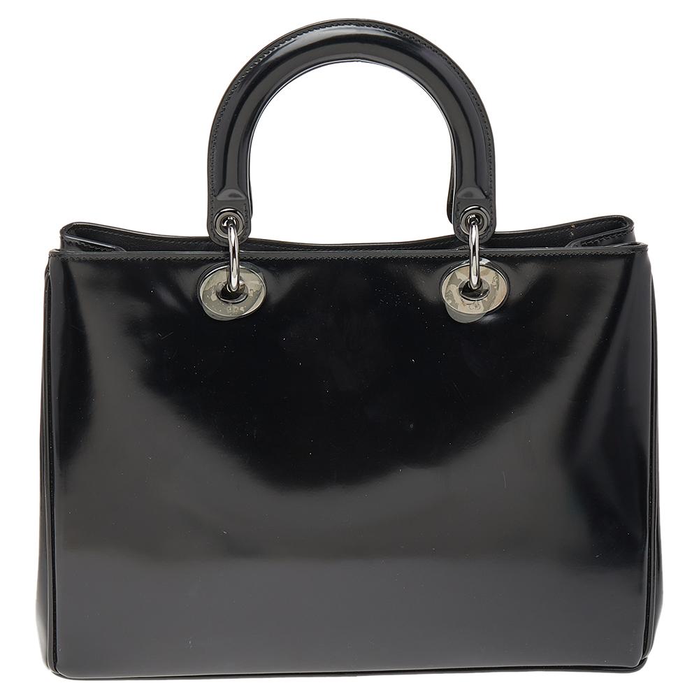 The Diorissimo bag from Dior is a piece that has never gone out of style. The patent leather bag comes in a classy black shade with black-tone hardware and Dior letter charms. It features double top handles, a shoulder strap, and protective feet at