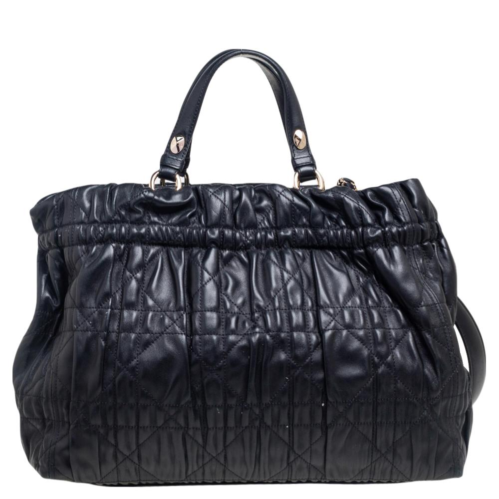 This Gaufre Delices bag from the House of Dior stands as a true testament to the label's longstanding prowess and aesthetic. This bag is created skillfully using black quilted Cannage leather on the exterior and flaunts a sturdy structure and