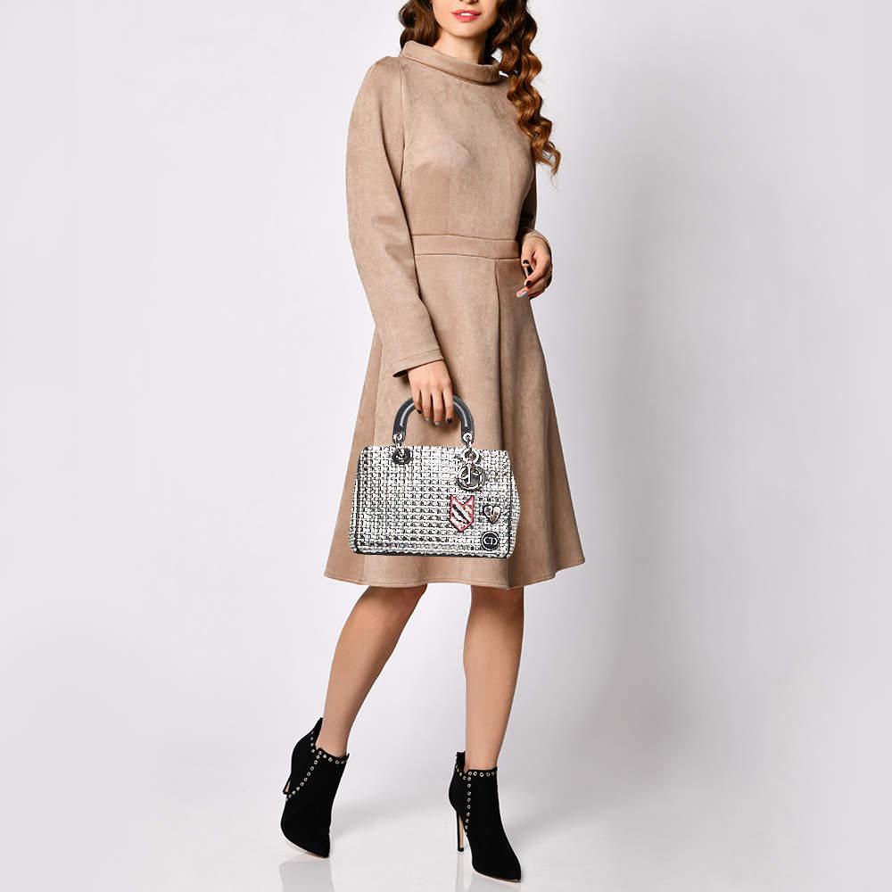 Este bolso Diorissimo de la Casa Dior es una creación atemporal que nunca pasará de moda. Está meticulosamente confeccionado en tweed y piel, y luce colgantes D.i.o.r dorados en la parte delantera. Dos asas dobles, un espacioso interior forrado de