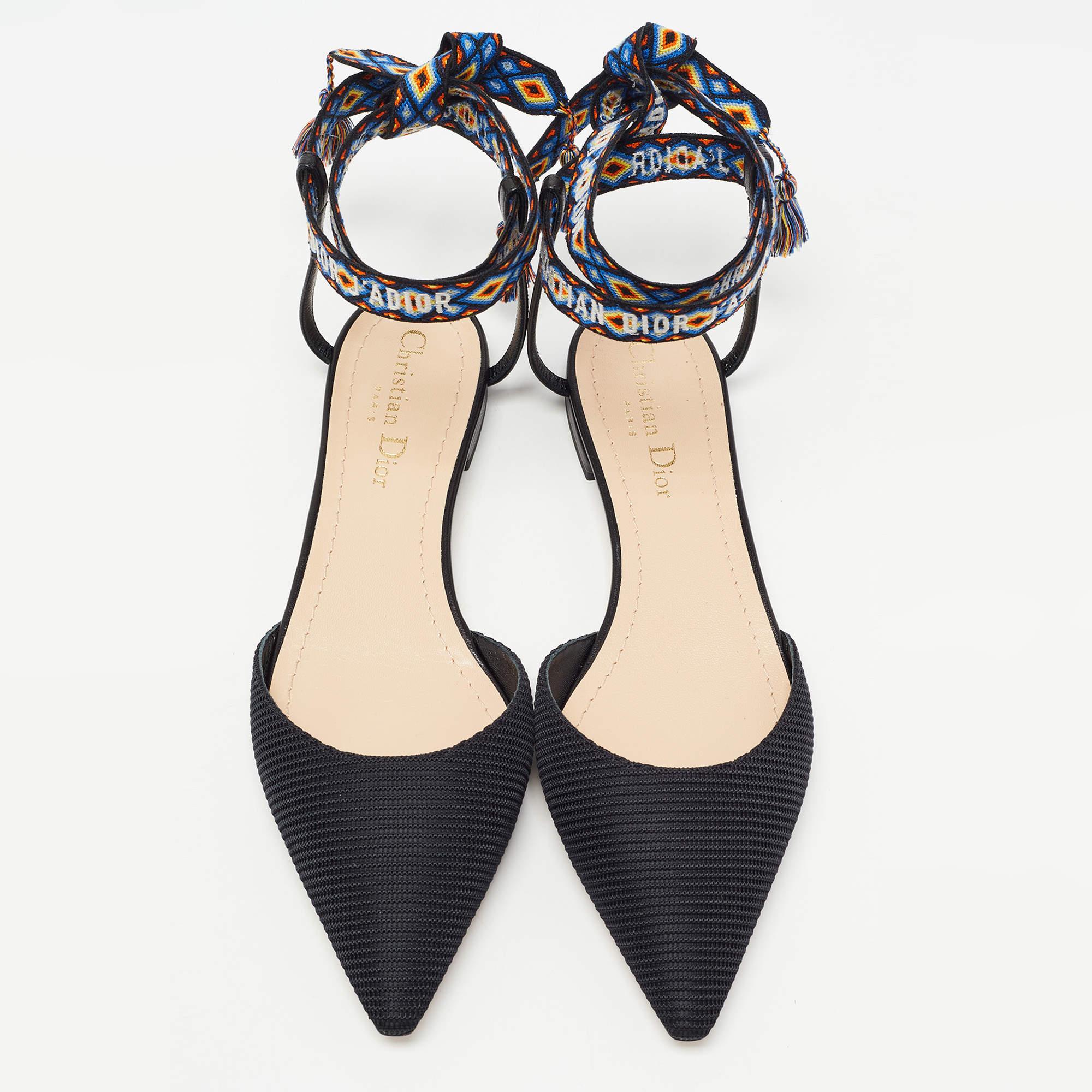 The J'adior collection from the House of Dior is one of the most beloved and celebrated creations of the label. These J'adior flats are made from black technical fabric and are adorned with a multicolored logo-printed ankle wrap feature. Sleek and