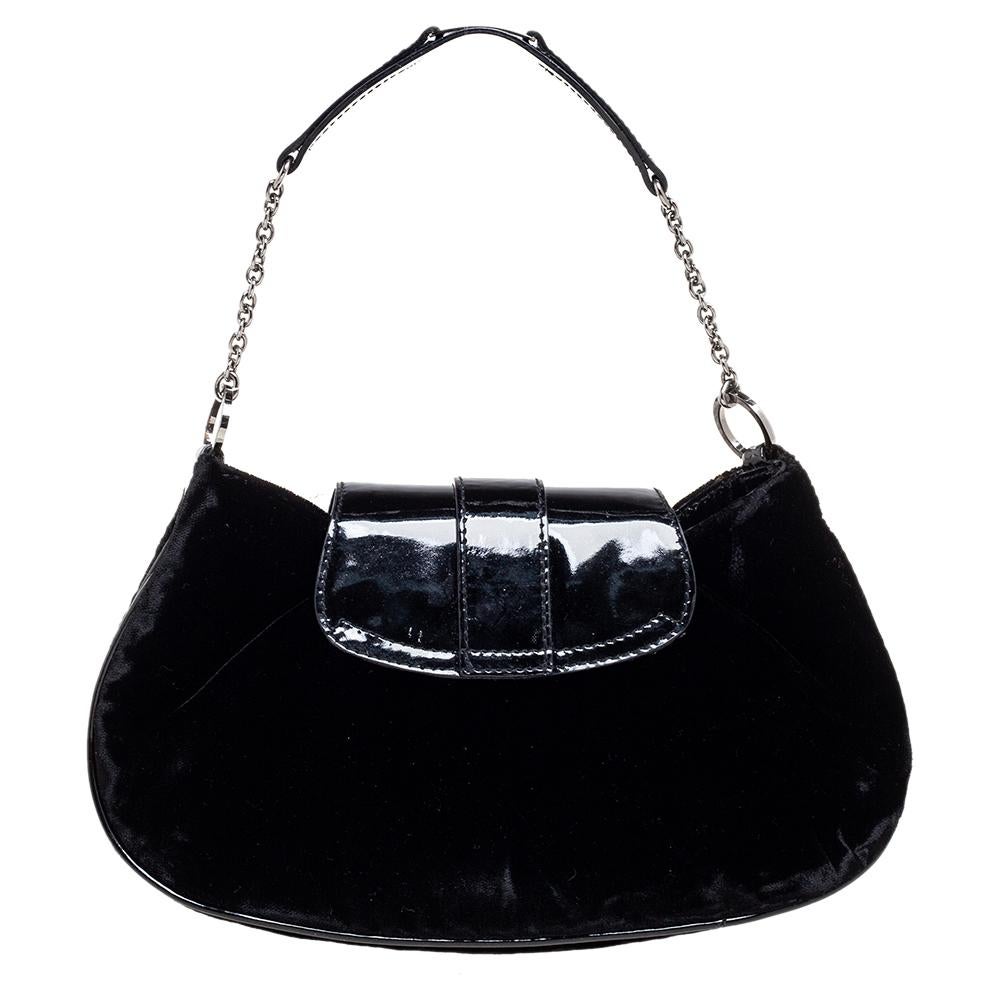 Handy and stylish, this pochette is from the house of Dior. It has been crafted from velvet and patent leather in a simple, compact silhouette and held by a single handle. The bag opens to reveal a nylon-lined interior for your phone, wallet, and