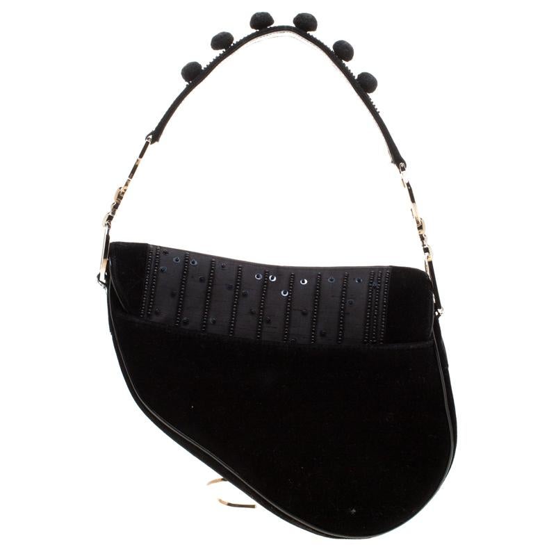 Originally designed by John Galliano, the Dior Saddle bag made a smashing comeback in the year 2018. Here, we have a splendid version of the bag. It is made from velvet, nylon and patent leather and embellished with pom poms. A single handle and a