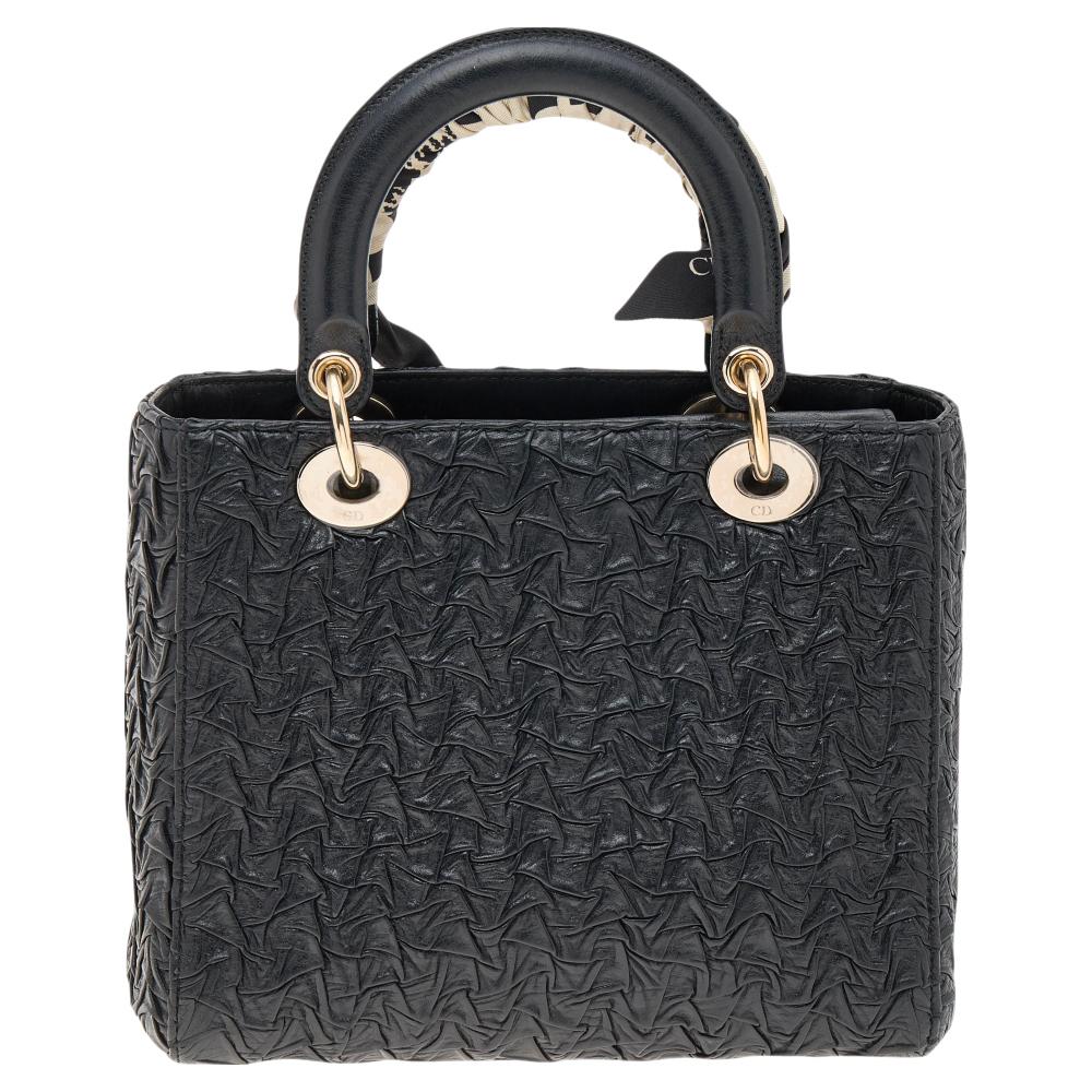The Lady Dior tote is a Dior creation that has gained recognition worldwide and is today a coveted bag that every fashionista craves to possess. This black tote has been crafted from wavy crinkled leather. It is equipped with a suede interior and