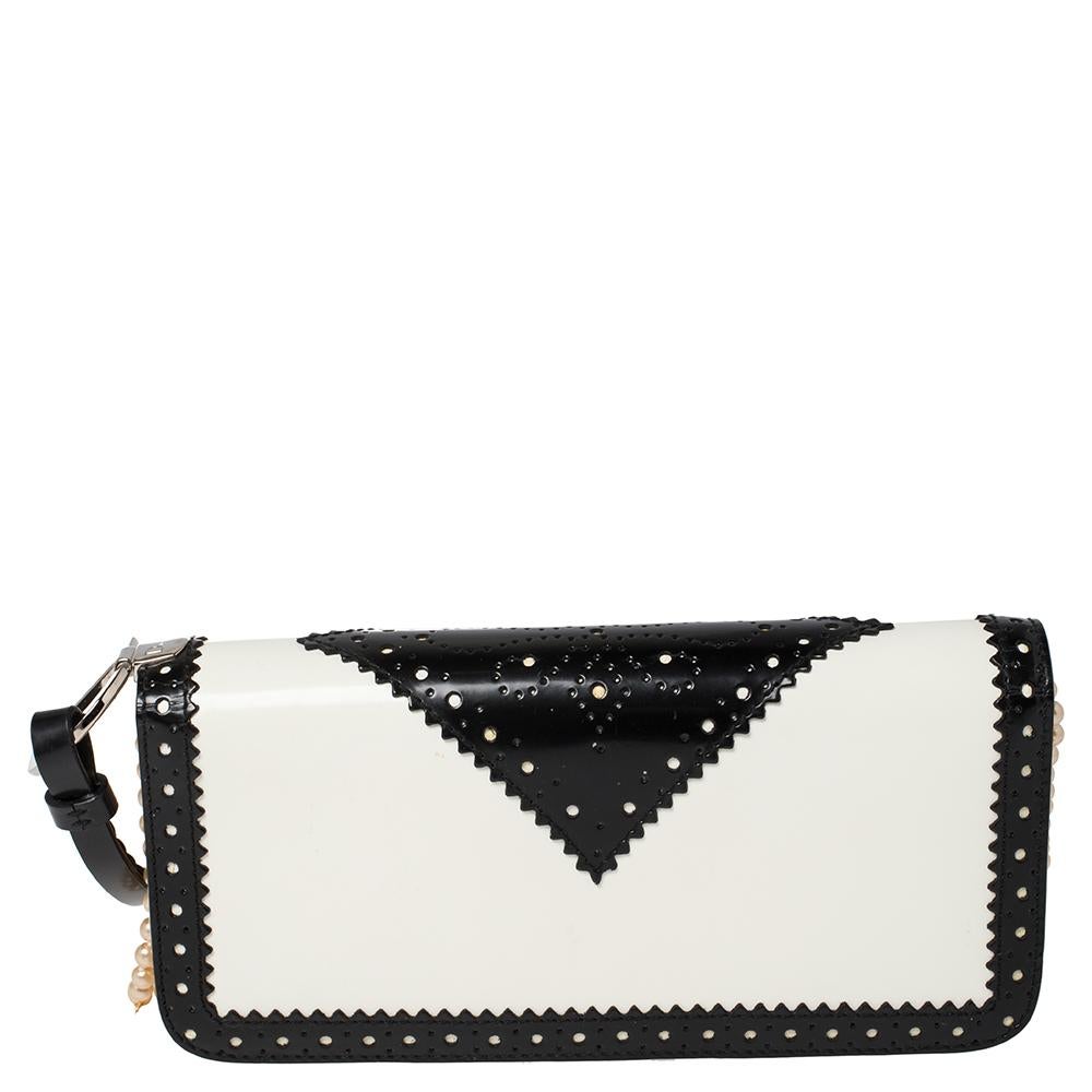 This is a must-have bag! It is expertly crafted from patent leather and features a brogue design on the exterior. This bag boasts a smooth satin lining. Turn heads with this beautifully designed bag from Dior. This black & white bag will seamlessly