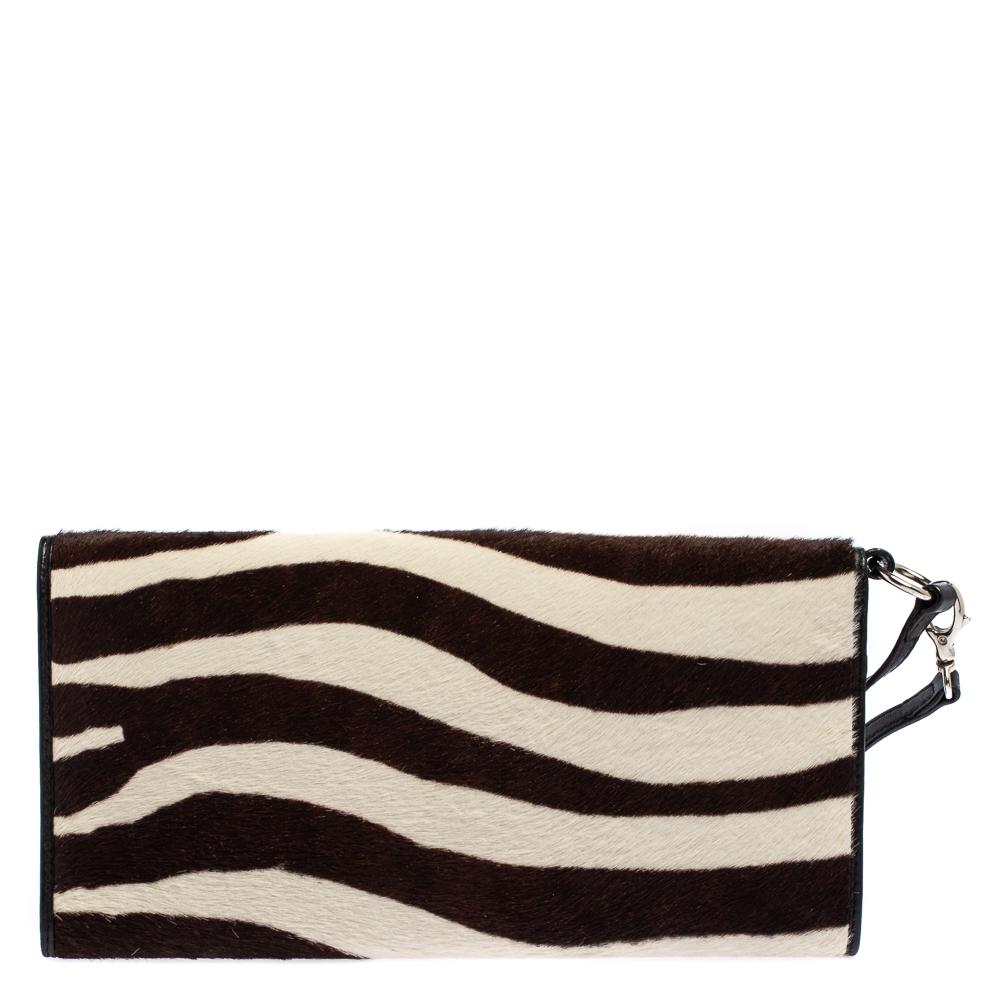 Every modern-day wardrobe needs a Dior creation like this. A practical and elegant clutch in lovely hues, this one is made from calf hair and leather. It is held by a wristlet, features a silver-tone lock on the front flap, and comes with a