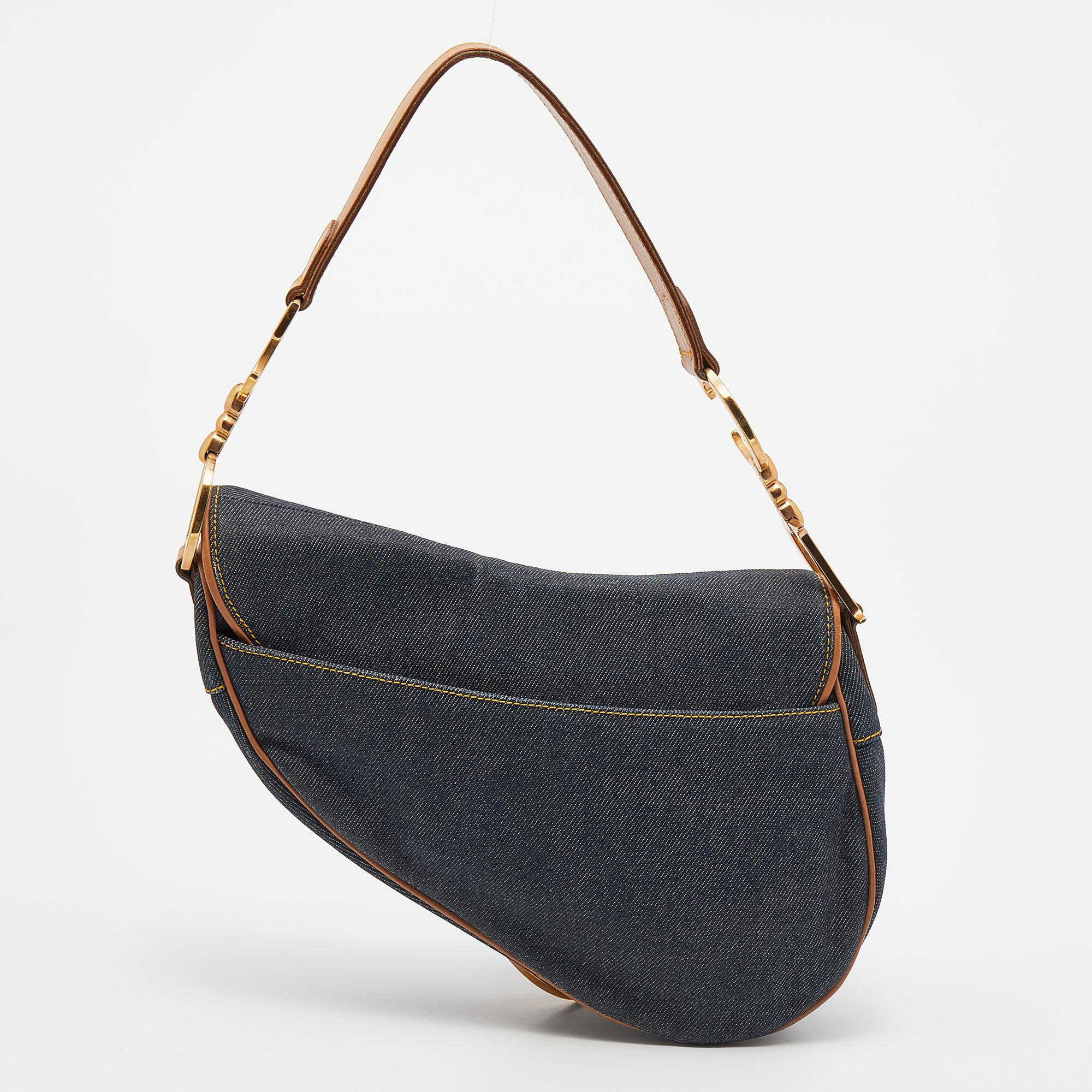 An example of timeless style and great design ideas, Dior's Saddle bag is sought after for all the right reasons. This Saddle bag for women is crafted using Denim in the iconic shape and it has CD letters to hold the single handle and a dangling D