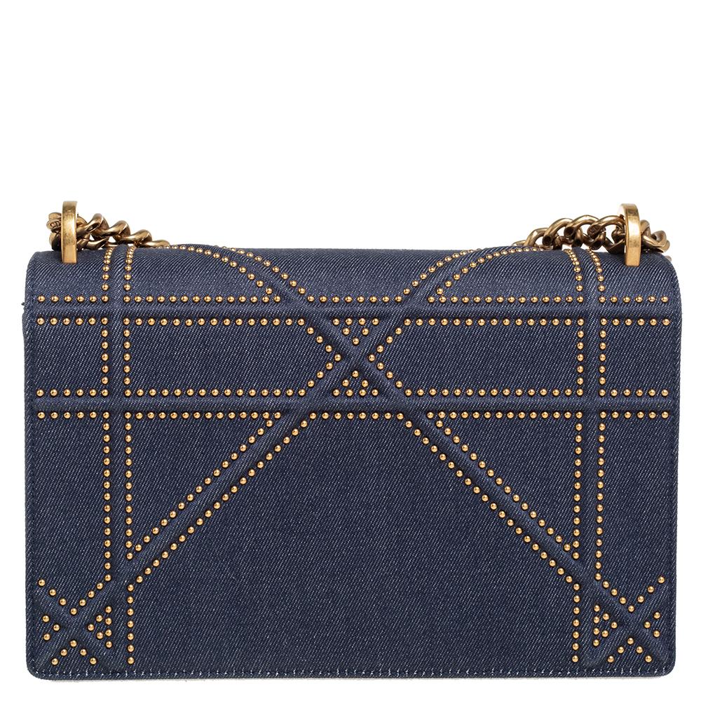 This Diorama bag is simply breathtaking! From its structured shape to its artistic craftsmanship, the bag sweeps us off our feet. It has been crafted from denim fabric and covered in gold-tone stud embellishments. A magnetic closure on the front