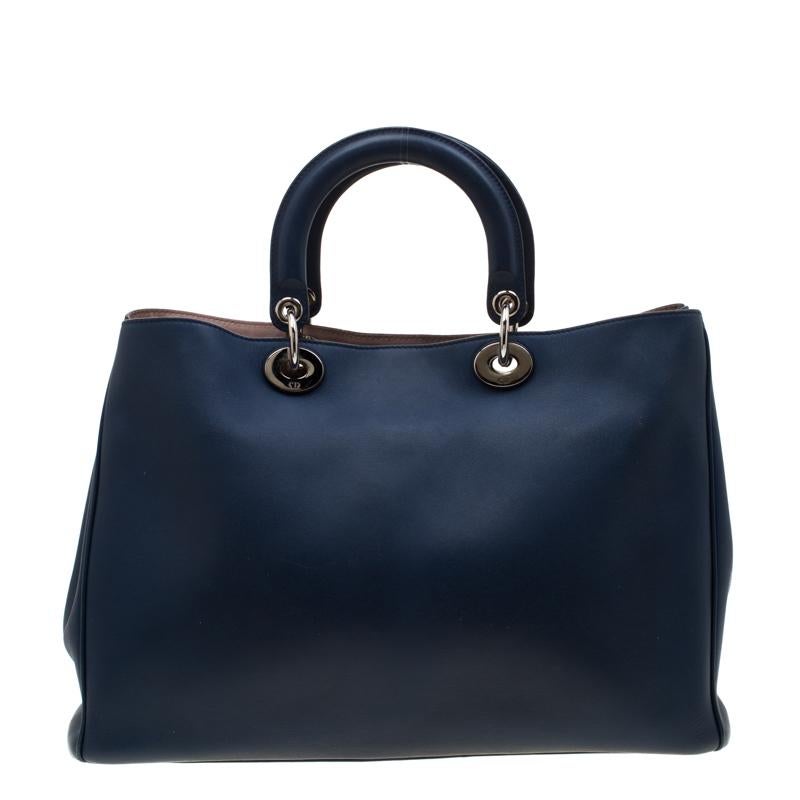 The Diorissimo bag from Dior is a timeless piece. The leather bag comes in a luxurious blue hue with gold-tone hardware and Dior letter charms. It features double top handles, a detachable shoulder strap and protective feet at the bottom. A snap