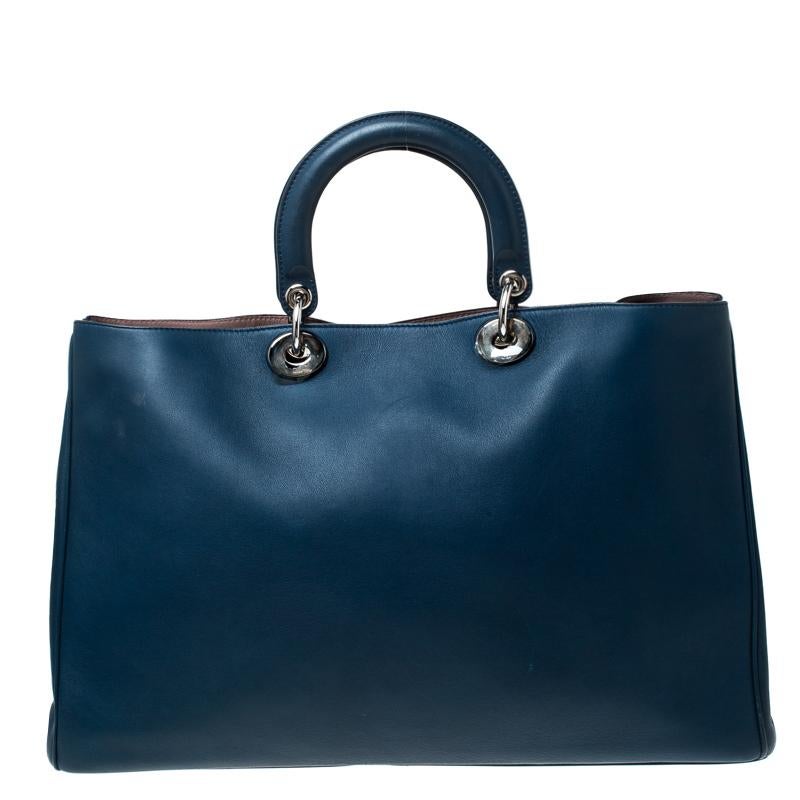 The Diorissimo bag from Dior is a timeless piece. The leather bag comes in a luxurious blue hue with silver-tone hardware and Dior letter charms. It features double top handles, a detachable shoulder strap and protective feet at the bottom. A snap