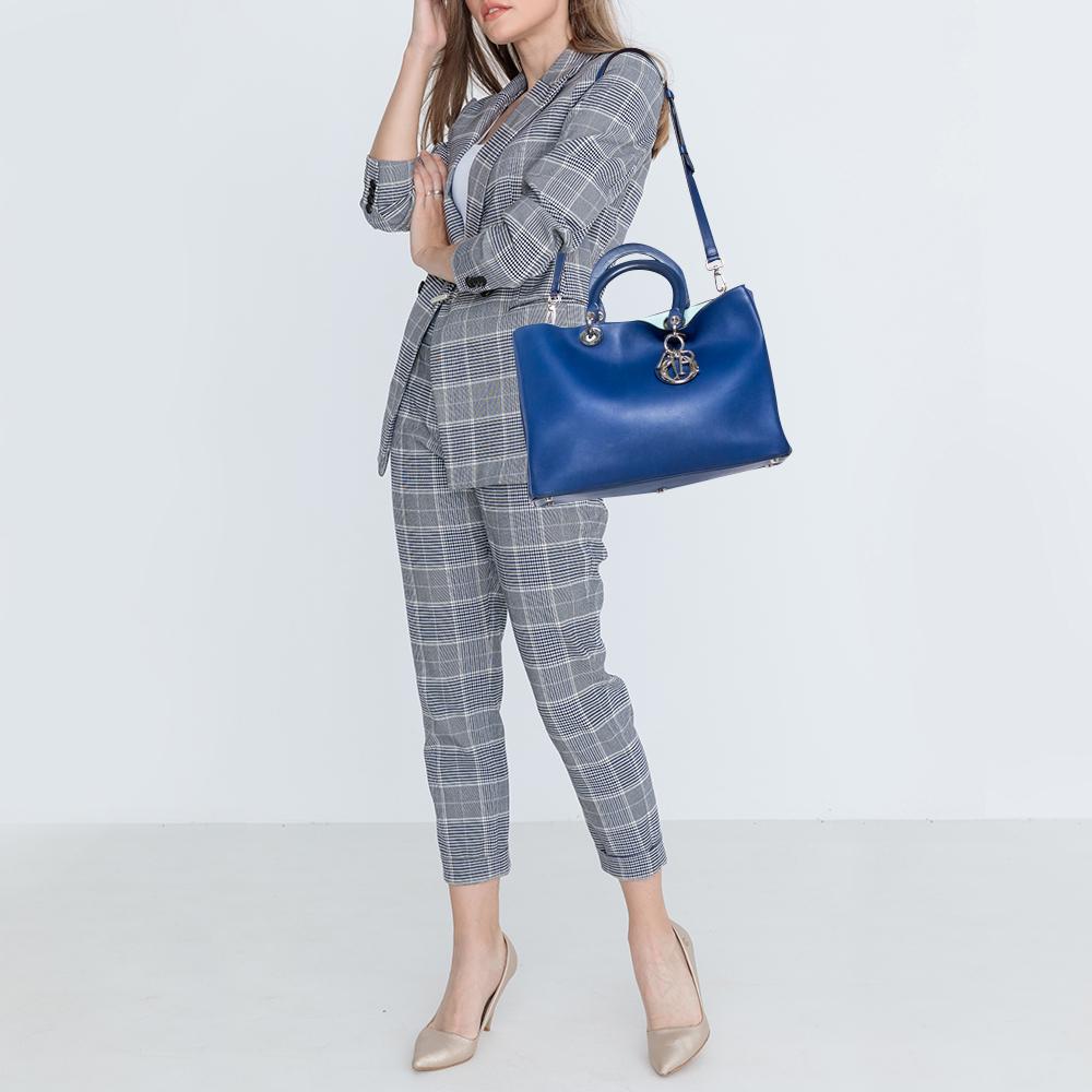 The Diorissimo shopper tote from Dior is a piece that has never gone out of style. The leather bag comes in a pleasing blue shade with silver-tone hardware and Dior letter charms. It features double top handles, a small pouch, and protective feet at