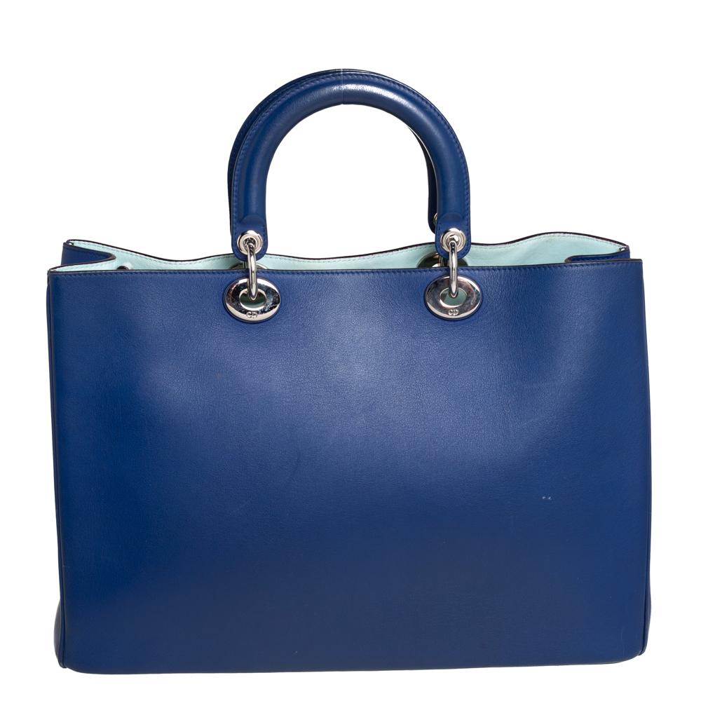 The Diorissimo shopper tote from Dior is a piece that has never gone out of style. The leather bag comes in a pleasing blue shade with silver-tone hardware and Dior letter charms. It features double top handles, a small pouch, and protective feet at