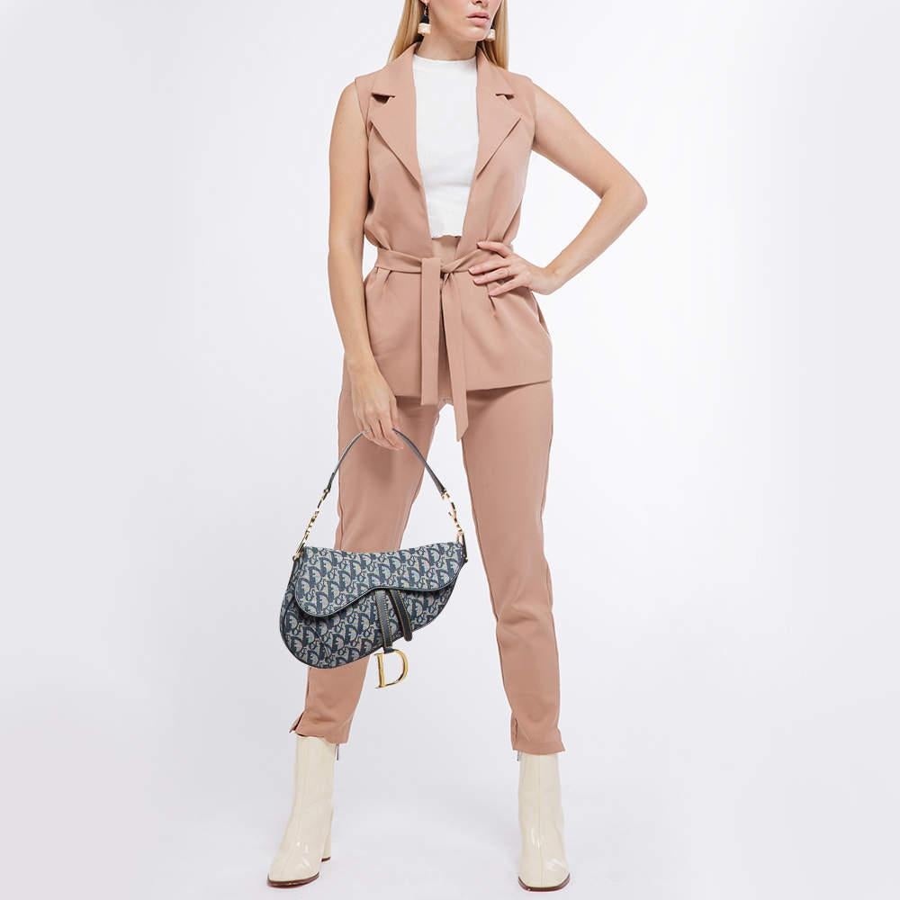 The Dior Saddle Bag is an iconic statement piece that combines timeless design with modern flair. Crafted in signature blue Oblique canvas this unique silhouette features a magnetic D stirrup closure and sleek leather accents. Perfect for both