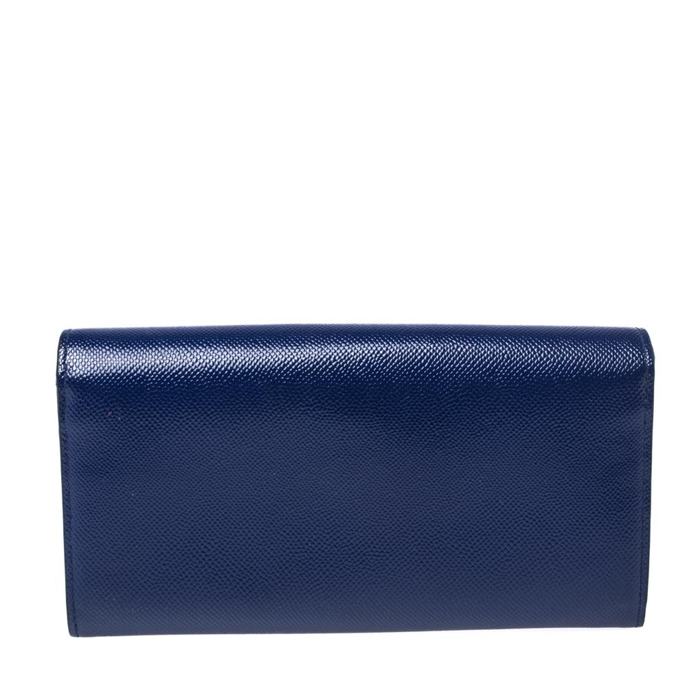 This small evening wallet clutch by Dior is beyond glamorous. With an exterior crafted from blue patent leather, it features Dior’s signature 'CD' logo on the front flap. Its interior is lined with leather & fabric and comes with a zip pocket, two