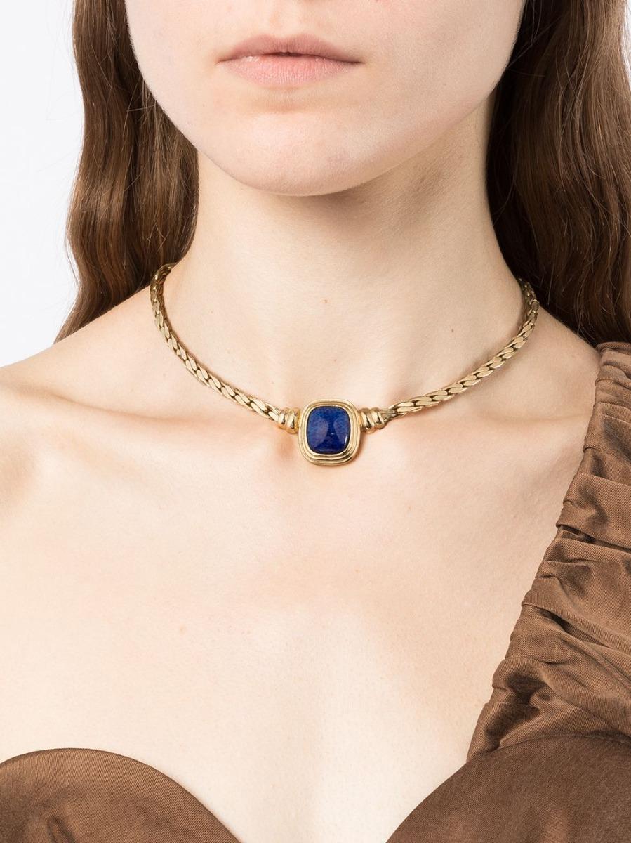 This pre-owned 1980s Christian Dior necklace features a gold plated metal chain with a large central blue marbled faux lapis lazuli stone with dark blue spots and sparkly veins, emulating the night sky.  This statement piece will take centre stage