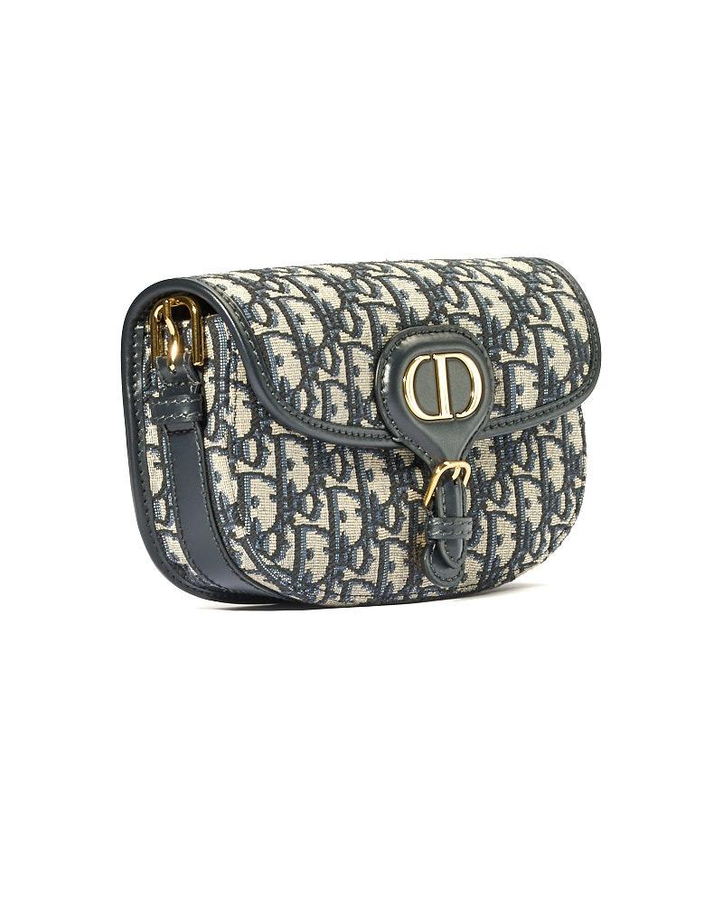 Borsa firmata Dior, Modello Bobby East-West, realizzata in tessuto con la classica fantasia Oblique e rifiniture in pelle blu con hardware dorati. Dotata di una patta frontale con classico logo del brand e chiusura a bottone calamitato, internamente