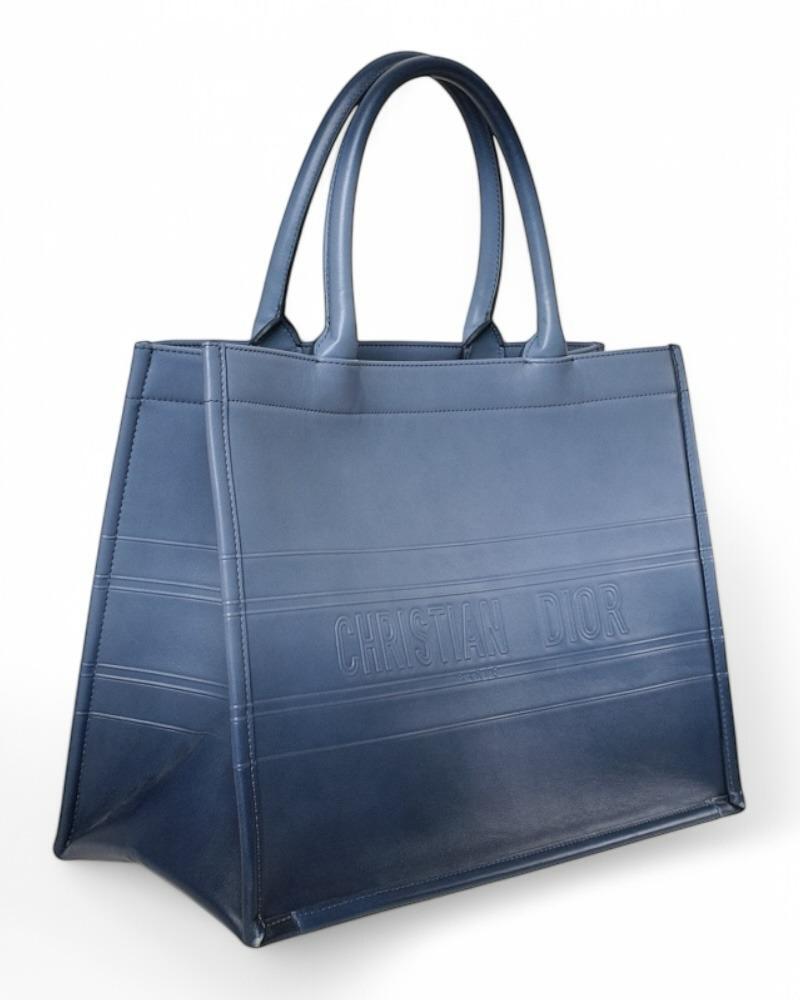 Dior designer bag, Book Tote model in size Medium. Made of smooth leather in shaded blue color. It has no closure, internally it is lined with tone-on-tone suede fabric, very roomy.  Equipped with a double rigid handle for convenient carrying by