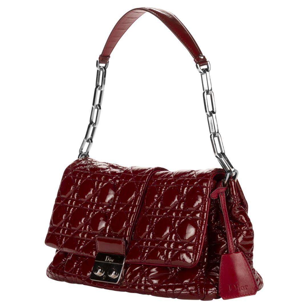 This Dior shoulder bag in rich bordeaux patent leather boasts a timeless quilted cannage design. Accented with silver-tone hardware and a secure push-lock closure, the interior reveals a canvas lining with three compartments and a zippered