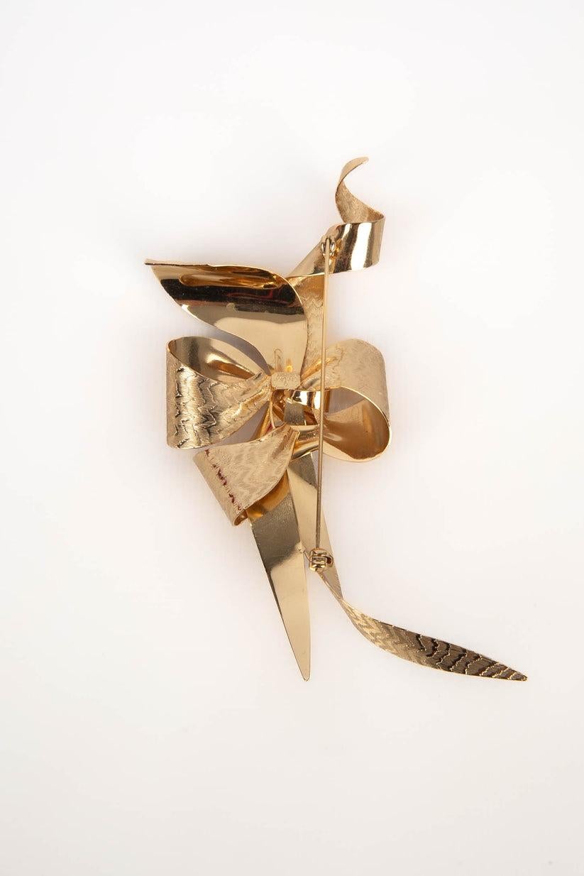 Dior - (Made in Germany) Golden metal brooch representing a bow.

Additional information:
Condition: Very good condition
Dimensions: 12 cm x 6 cm

Seller Reference: BR34