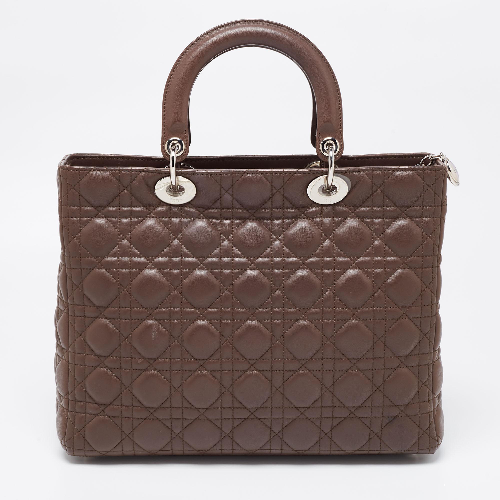 A timeless status and great design mark the Lady Dior tote. It is an iconic bag that people continue to invest in to this day. We have here this large Lady Dior tote crafted from brown Cannage leather. The bag is complete with two top handles, a