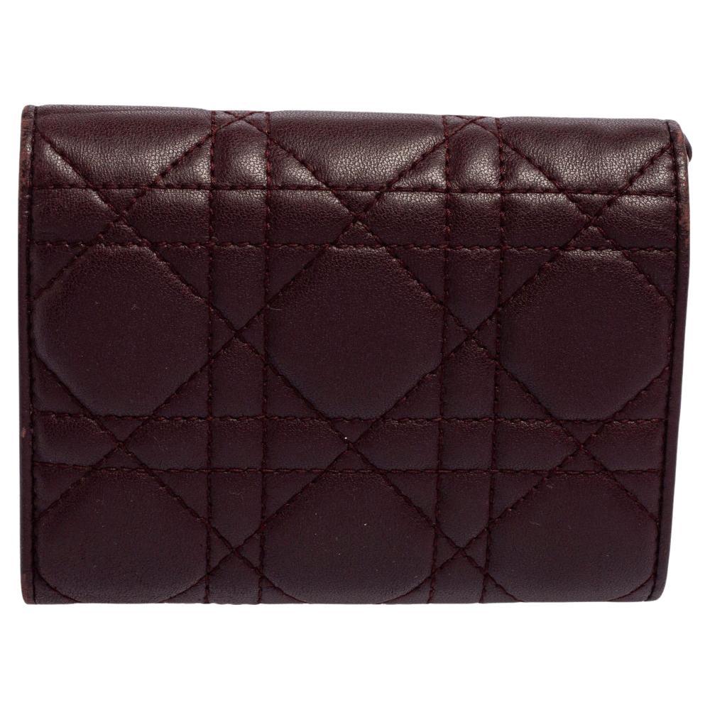 Bring Dior's signatory elegance and aesthetic to your accessory repertoire with this beautiful Lady Dior wallet. It is made from burgundy Cannage leather with gold-toned hardware enhancing its shape. This wallet opens to a fabric-leather interior.