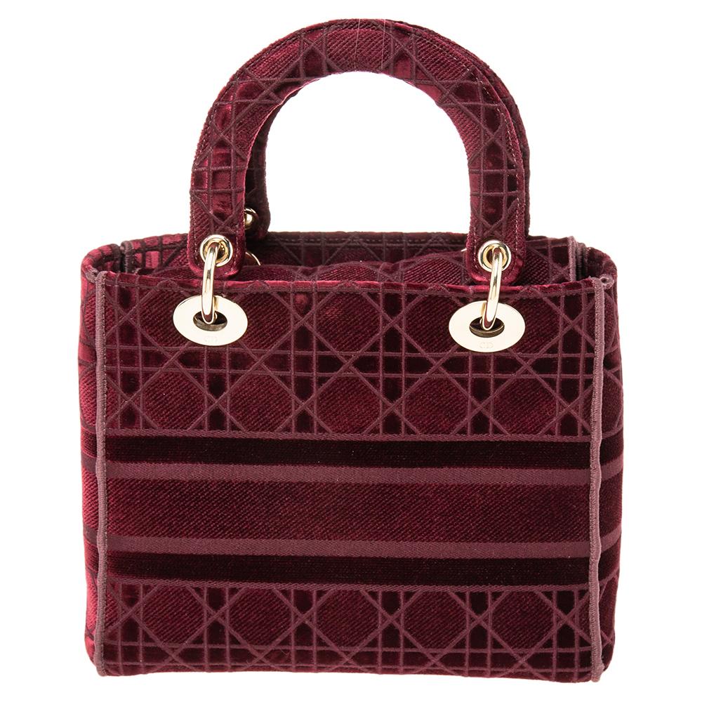 The Dior Lady D-Lite tote is timeless yet modern in its appeal! This version has a burgundy exterior covered in the Cannage motif. The structured silhouette is finished off with the 'CHRISTIAN DIOR PARIS' lettering on the front, dual handles, a