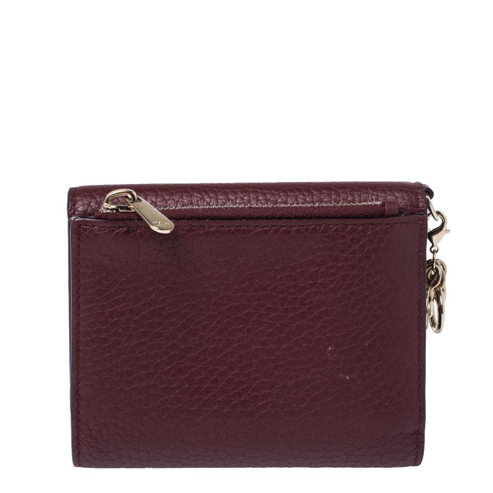 This Diorissimo envelope wallet is a compact and fashionable creation from Dior. Made from fine burgundy leather, it has a pebbled effect and multiple card holder slots. It opens with a snap, features Dior charms in gold-tone hardware and is a great