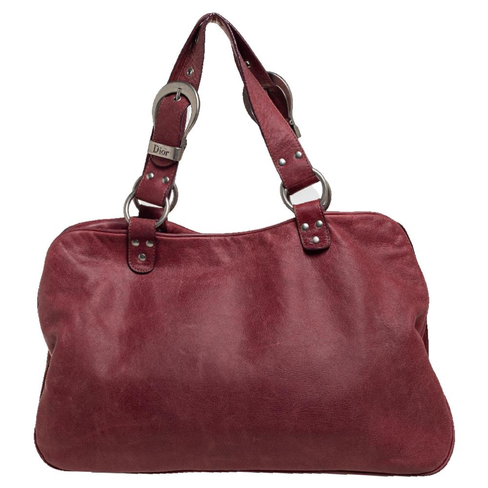 From the house of Dior comes this Double Saddle bag which is an excellent blend of elegance and style. It comes in a beautiful burgundy hue, perfect for making a statement. The bag features a chunky buckle on the front and a nylon-lined interior.