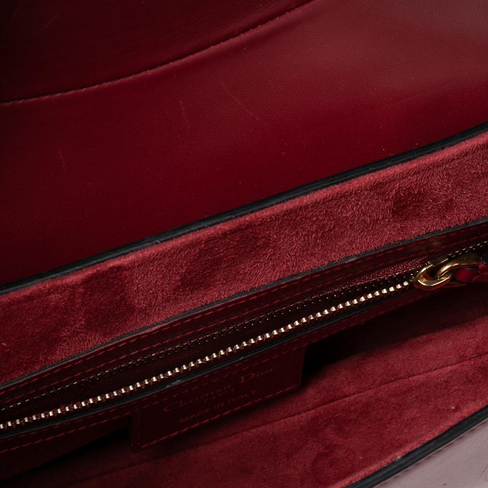 An example of timeless style and great design ideas, Dior's Saddle bag is sought after for all the right reasons. This burgundy Saddle bag for women is crafted using leather in the iconic shape and it has the signature dangling D on the flap and