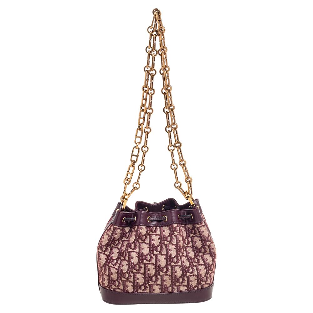 A handbag that taps into the major trends of the season with the Oblique motif detail all over and the CD chunky chain strap! The Dior bucket bag is crafted from canvas and defined with leather in a regal burgundy shade. It has a drawstring closure