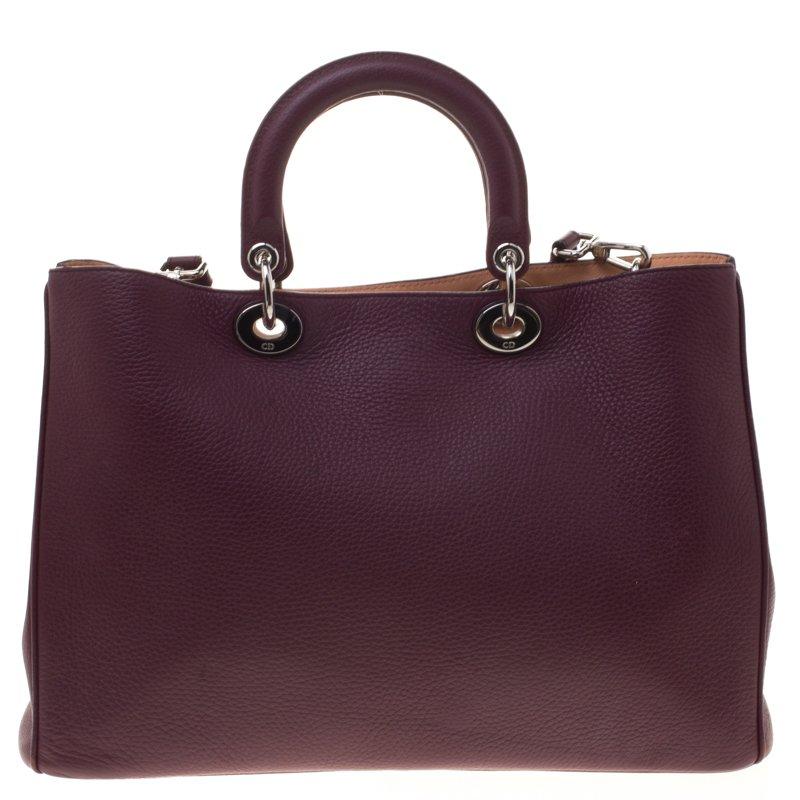 Set in a contemporary design and style, this burgundy large Diorama Shopper tote from Christian Dior is absolutely mesmerizing. With a new twist to the classic bags, this bag is crafted from leather and features a pebbled texture all over. It comes