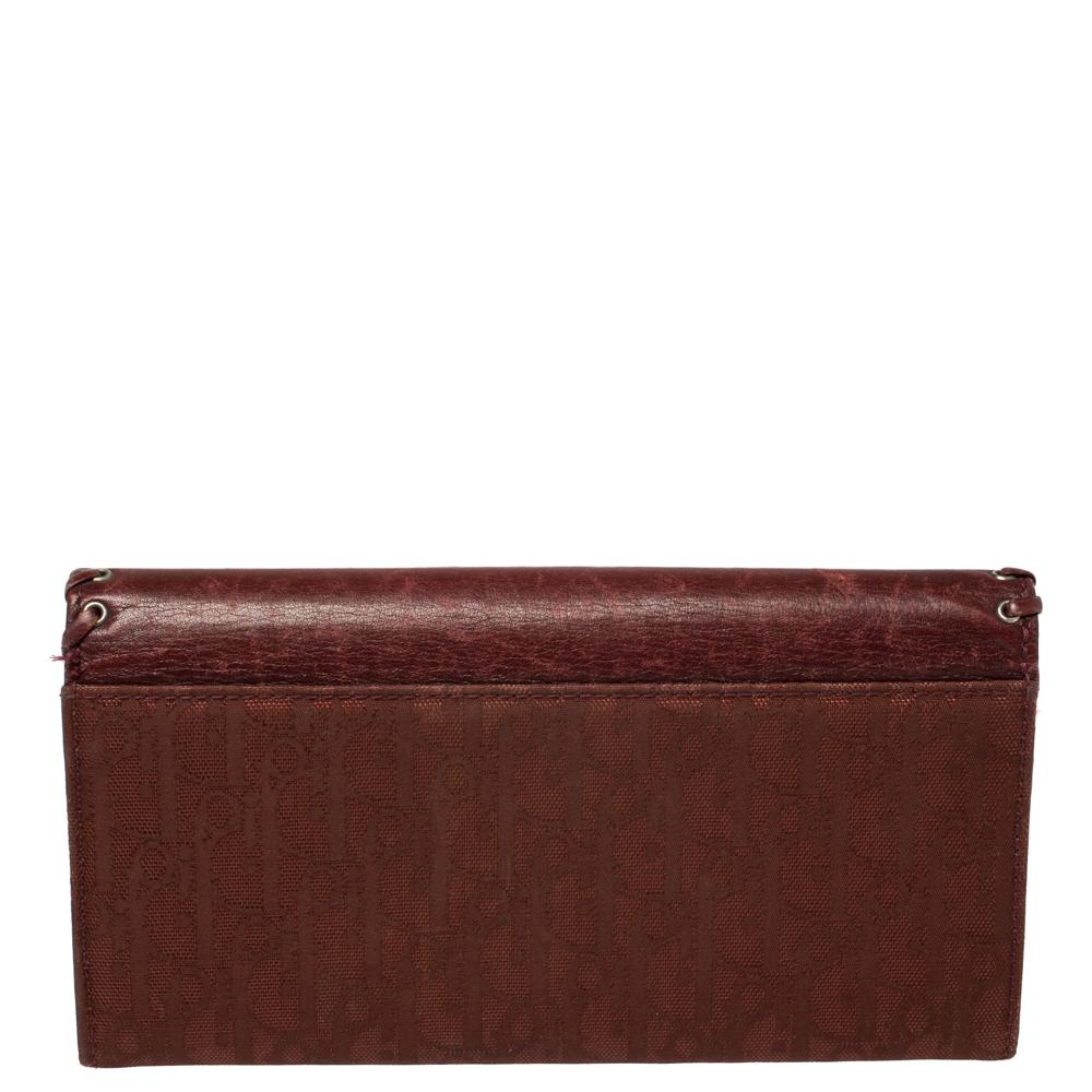 This stylish and functional continental wallet hails from the house of Dior. It has been crafted from signature canvas and woven leather trims. The burgundy hue elevates the design while the iconic elements make it covetable. It has a front flap