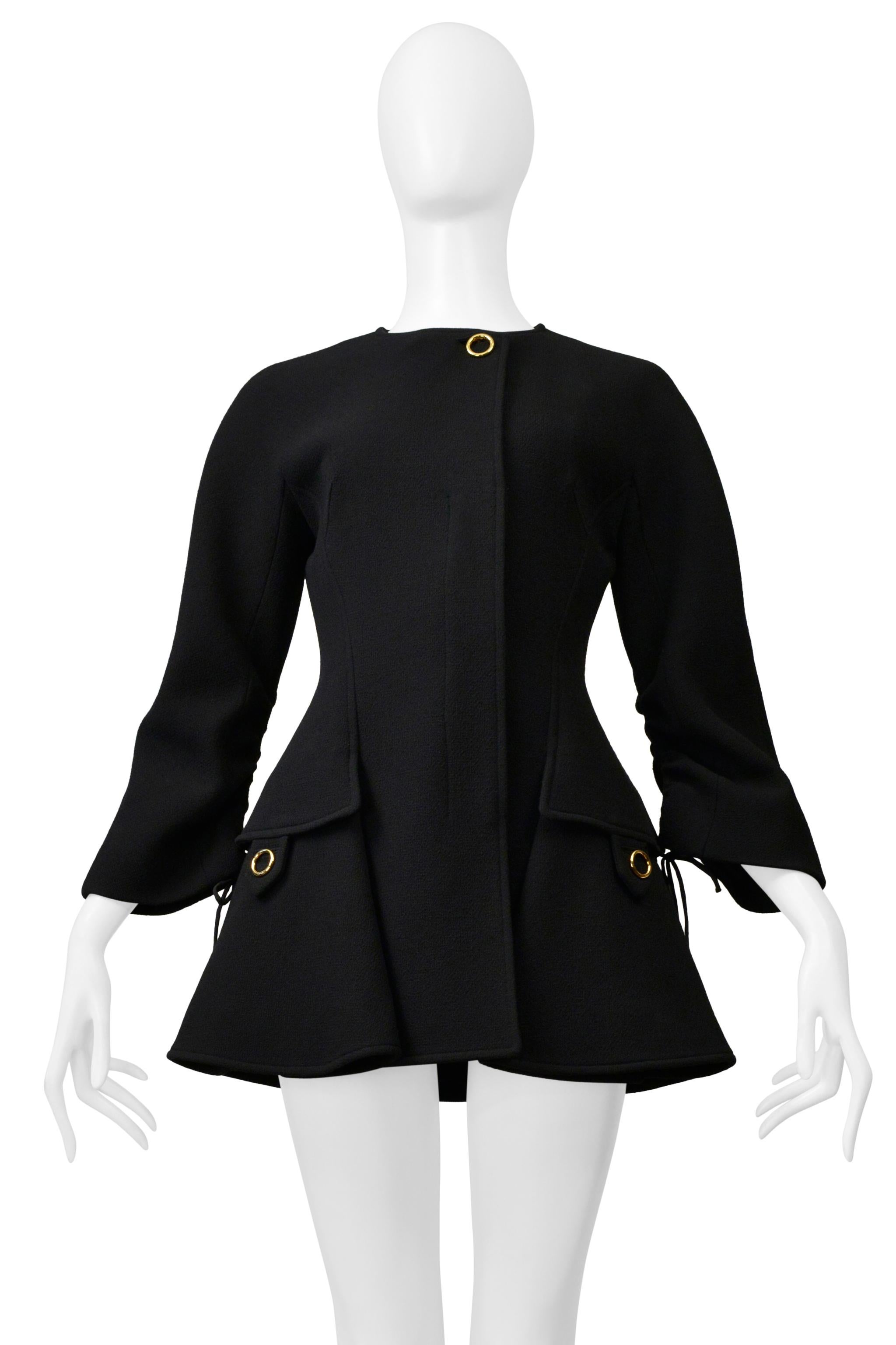 Resurrection Vintage è lieta di offrirti un cappotto modernista a-line in lana nera di Christian Simons for Christian Dior, caratterizzato da maniche con coulisse e finiture dorate, chiusure rotonde dorate, abbottonatura frontale nascosta, tasche