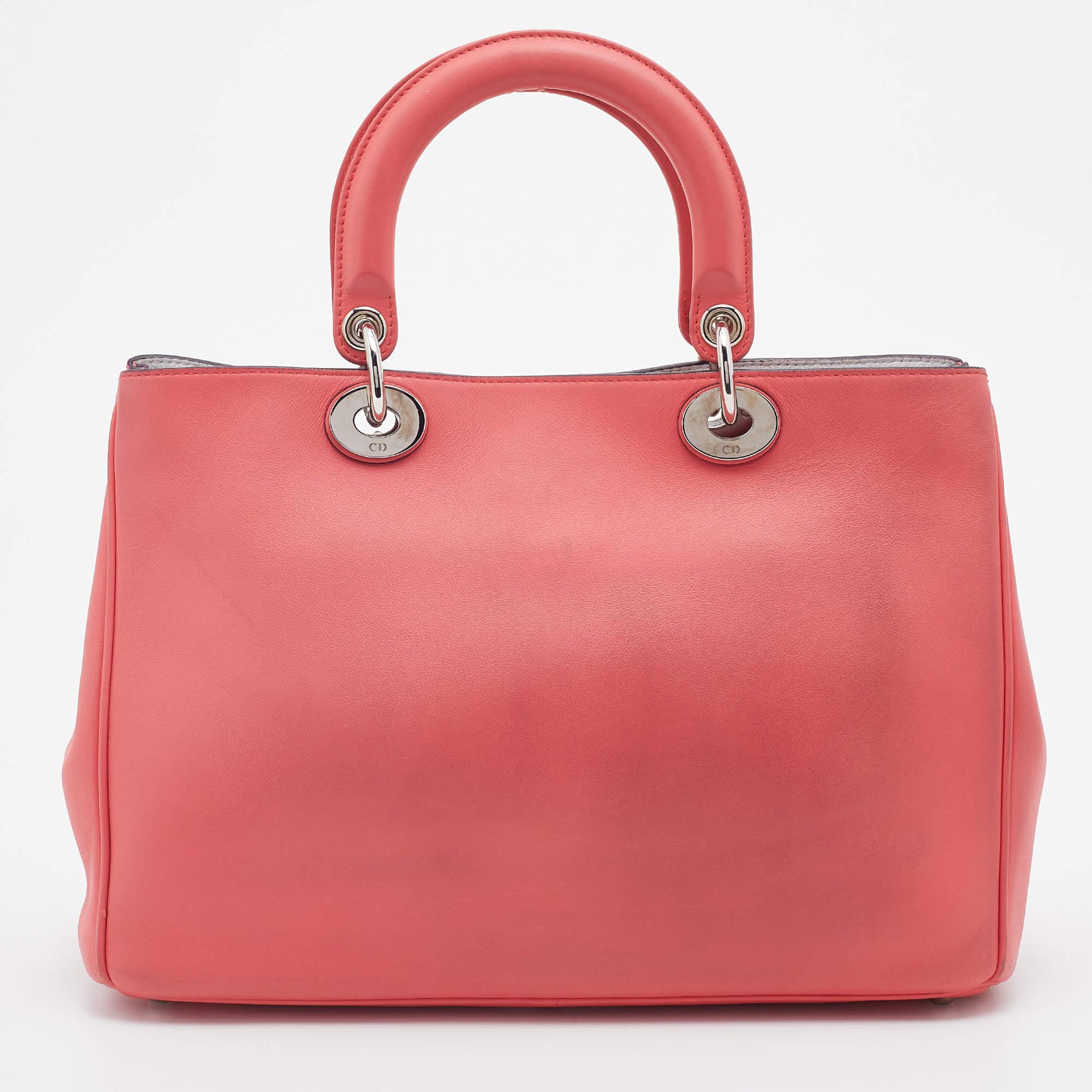 The Diorissimo shopper tote from Dior is a piece that has never gone out of style. This leather tote here comes in a coral pink hue with silver-tone hardware and the iconic Dior letter charms. It features double top handles, a small matching pouch,