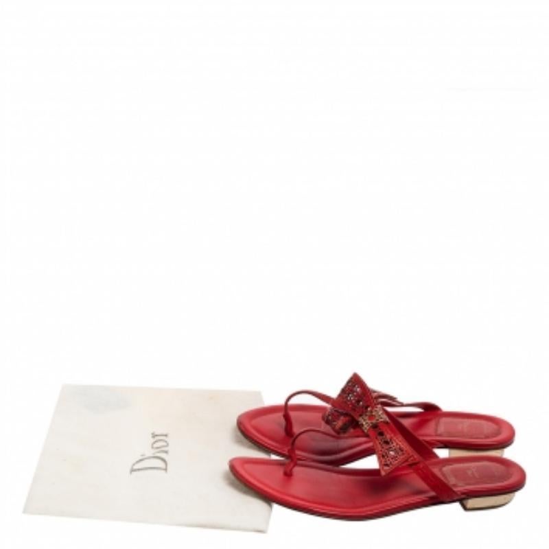 Incorporez charme et prestance à vos tenues décontractées en portant ces magnifiques chaussures plates de Dior. Confectionnées en cuir rouge corail, ces tongs sont ornées d'un nœud Cannage et de ferrures dorées. Elles sont à enfiler. Gardez vos