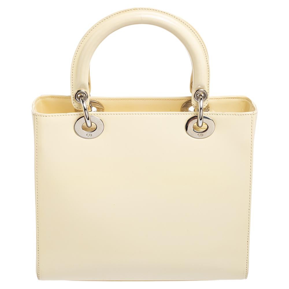 A timeless status and great design mark the Lady Dior tote. It is an iconic bag that people continue to invest in to this day. We have here this medium Lady Dior tote crafted from cream glazed leather. The bag is complete with two top handles, a
