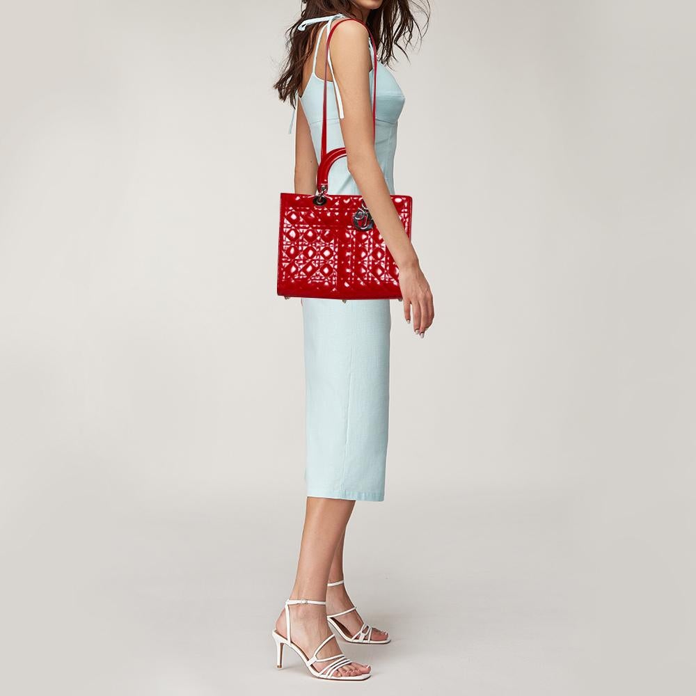 Die Lady Dior Tote ist eine Kreation von Dior, die weltweit Anerkennung gefunden hat und heute eine begehrte Tasche ist, die jede Fashionista unbedingt haben möchte. Diese purpurrote Tote wurde aus Lackleder gefertigt und trägt das charakteristische
