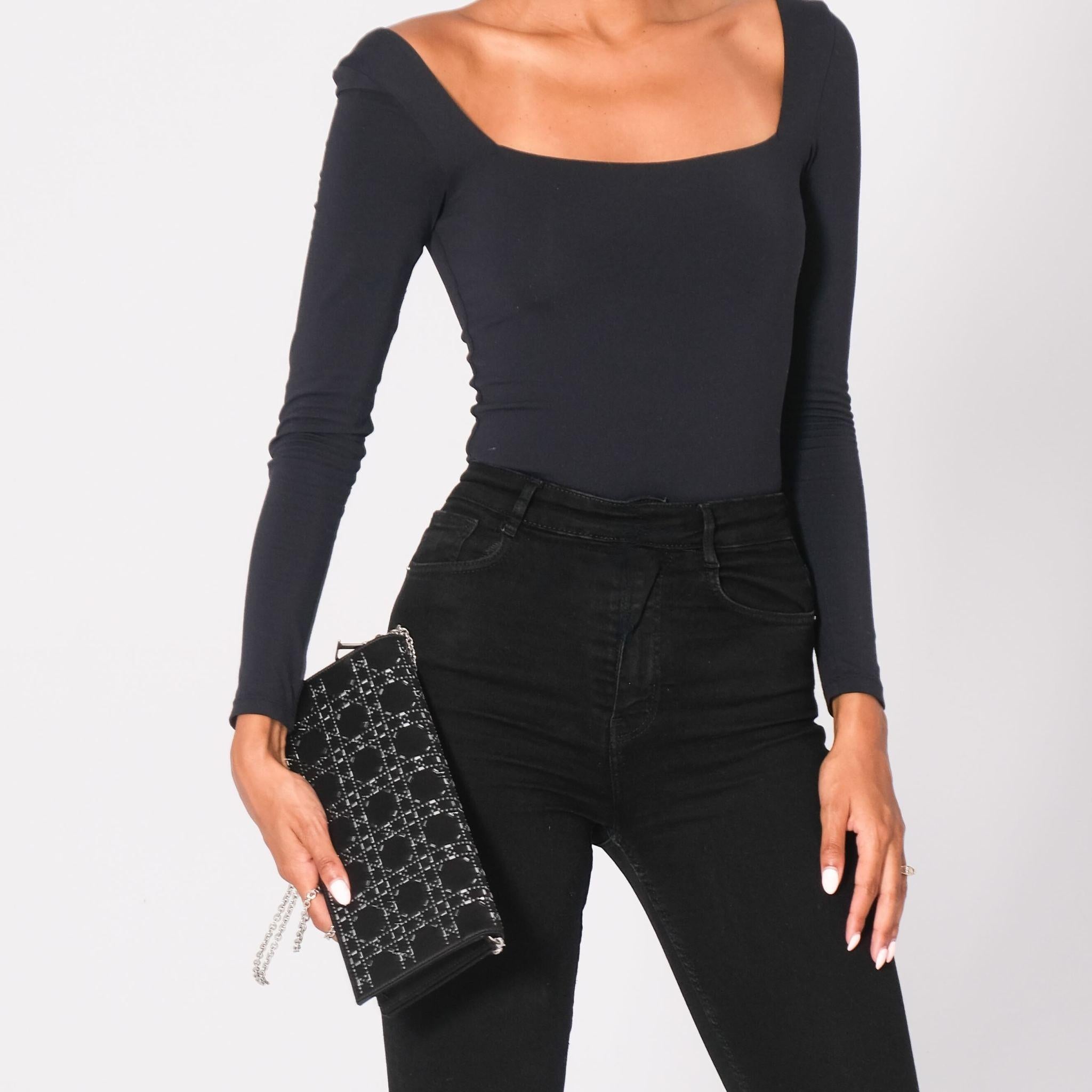 This Dior shoulder bag from the 2016 collection by Maria Grazia Chiuri is constructed of black satin with silver-tone hardware. It features a chain-link shoulder strap and crystal embellishments. The bag has a front flap with snap closure that opens