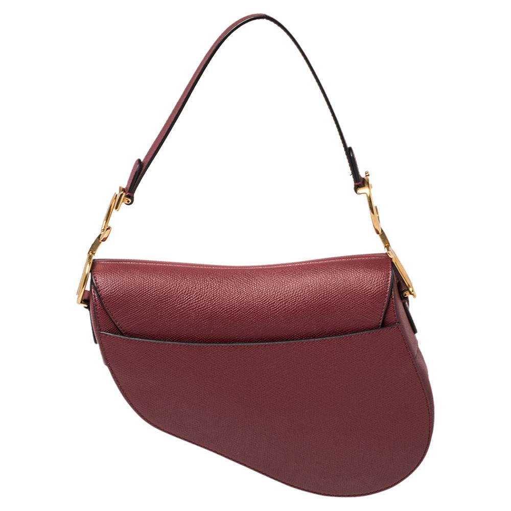 La selle Dior a fait un énorme retour en 2018 et elle est restée dans le vent. Pour vous permettre de suivre la tendance de la selle:: voici une superbe version en cuir rouge foncé. Une poignée unique et un intérieur en tissu résument la création.