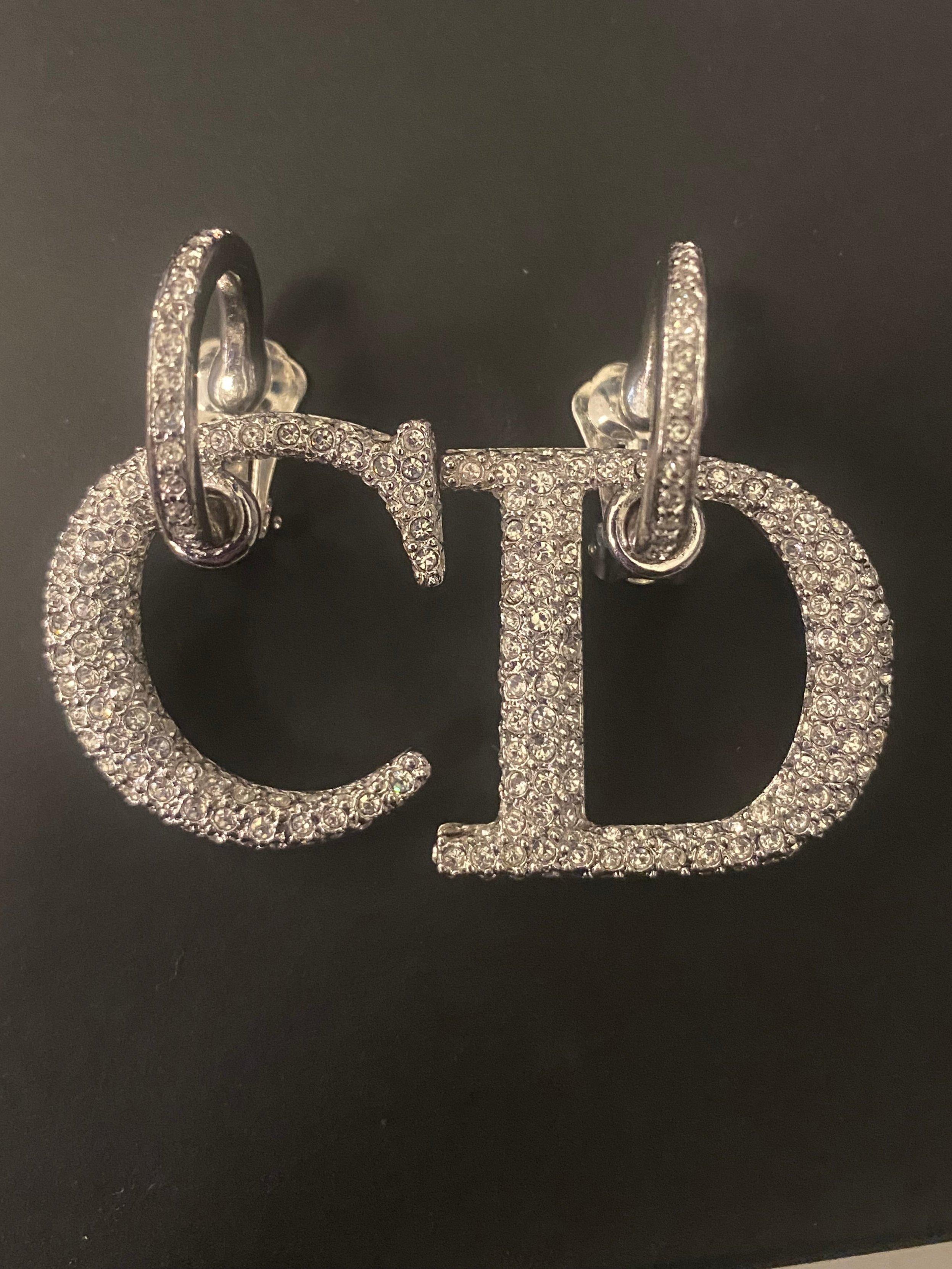 Christian Dior clip on earrings from the eponymous brand. Diamanté covered silver toned metal 'C' and 'D' letters dangle from small, embellished hoops. Branded 'Dior' on the clip on fastening. Letters 3cm drop. Circa 2000. Very good condition, some