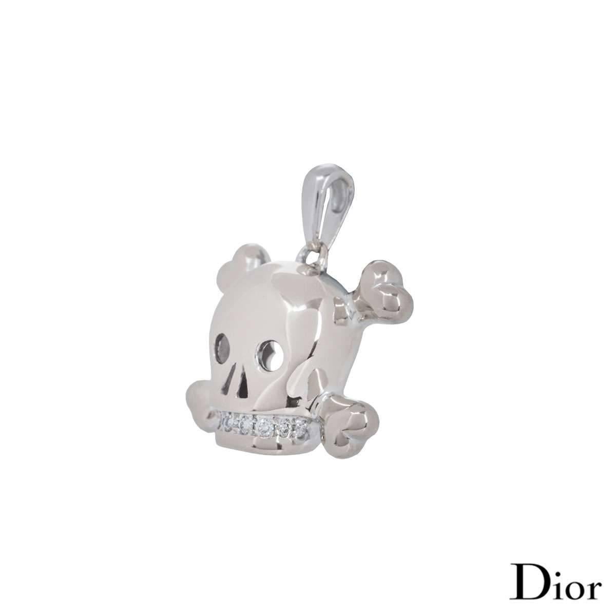 A beautiful 18k white gold skull pendant by Dior, part of the Tete De Mort collection. The pendant has a skull and crossbones design with round brilliant cut diamonds as teeth in a claw setting. There are a total of 8 diamonds weighing 0.16ct,