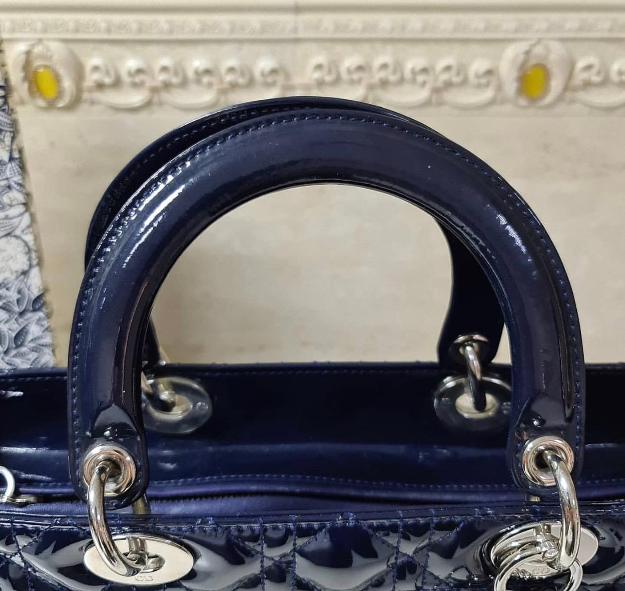 This sophisticated and feminine Lady Dior tote in your hand is apt for the perfect Dior look. Crafted in patent leather, it is accented with quilted pattern and silver-tone hardware. It features signature Dior charms, two round handles, a detachable