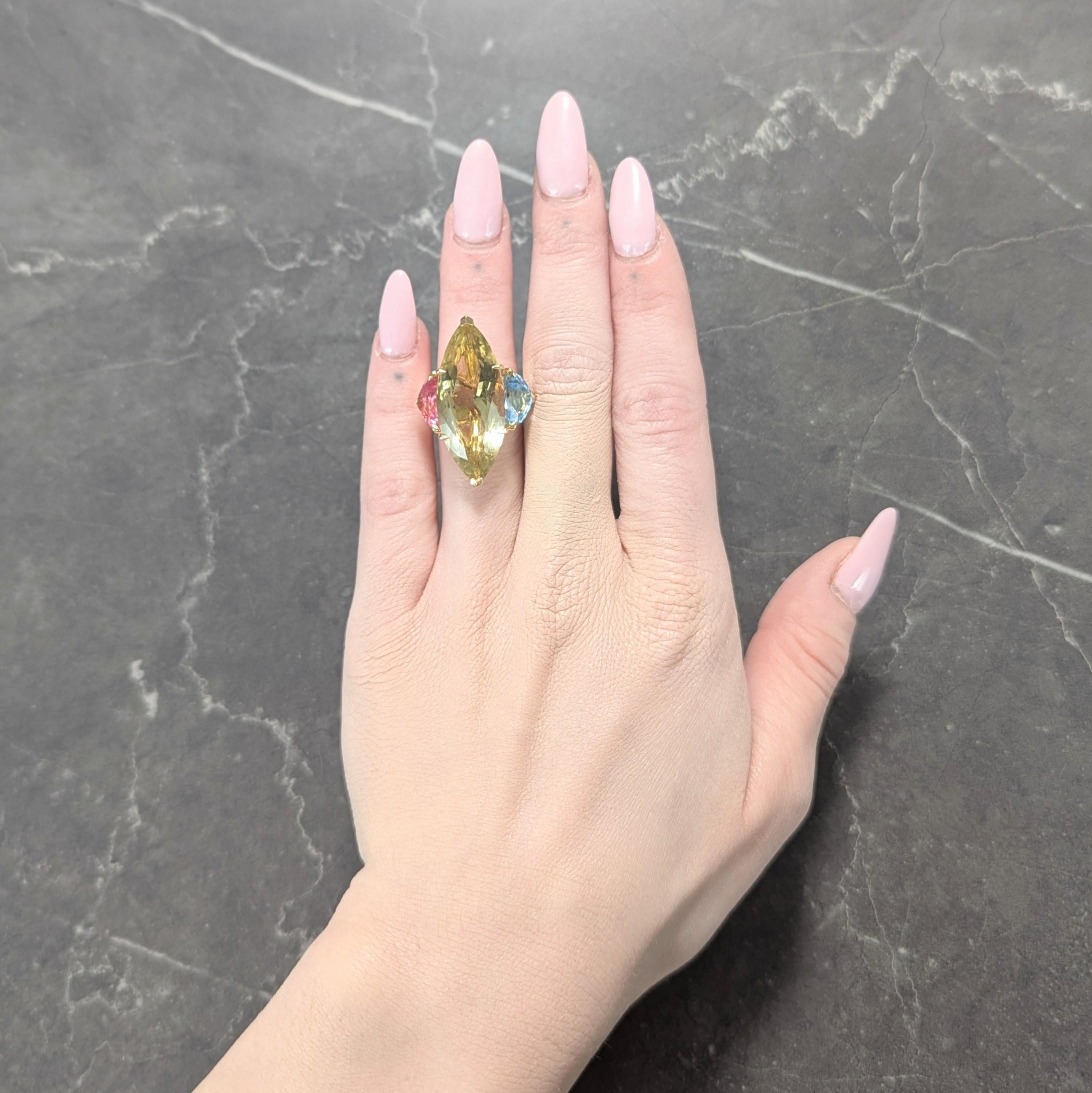 Al centro un quarzo limone tagliato a navetta di 13,0 x 30,0 mm - trasparente giallo verdastro.
Incastonato con rebbi a forma di artiglio in un cesto di filo metallico e affiancato da spalle in pietra multi-gemma con taglio trillion.
Composto da una