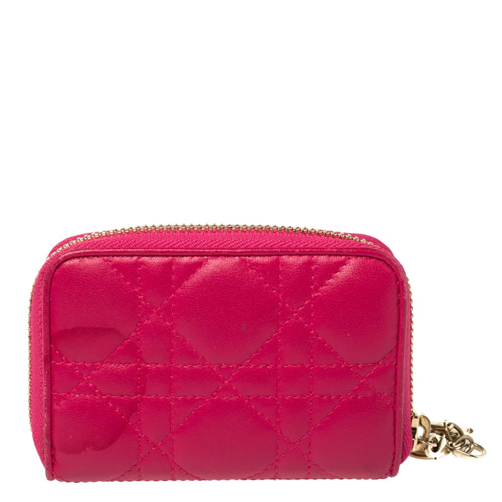 This Dior wallet is conveniently designed for everyday use. Crafted from Cannage-detailed leather in a fuchsia shade, the wallet has a zip closure with DIOR letter charms on the zip pull. It opens to reveal multiple slots for you to neatly arrange