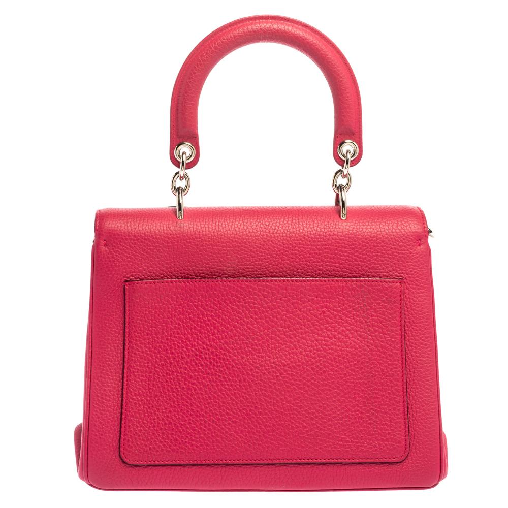 Pretty in fuchsia pink, this Dior bag is crafted from leather and designed with a front flap and a single top handle. The leather-lined interior houses an open compartment that can easily accommodate your daily essentials and the bag is complete
