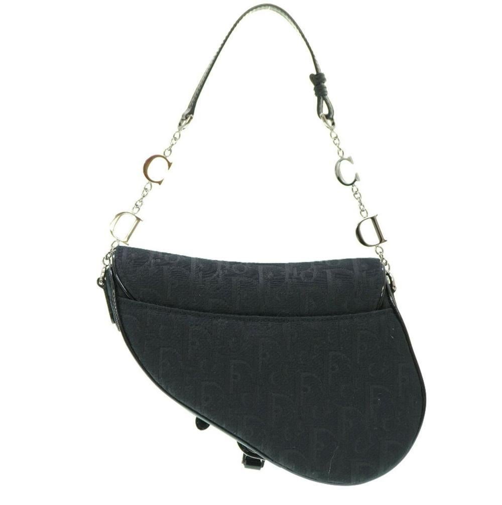 Esta edición limitada de la mini bolsa Saddle de Dior está bordada a mano y diseñada por John Galliano. El bolso presenta lona jacquard oblicua negra, acabados en piel negra, herrajes plateados y colgantes con el logotipo. El bolso está acabado con