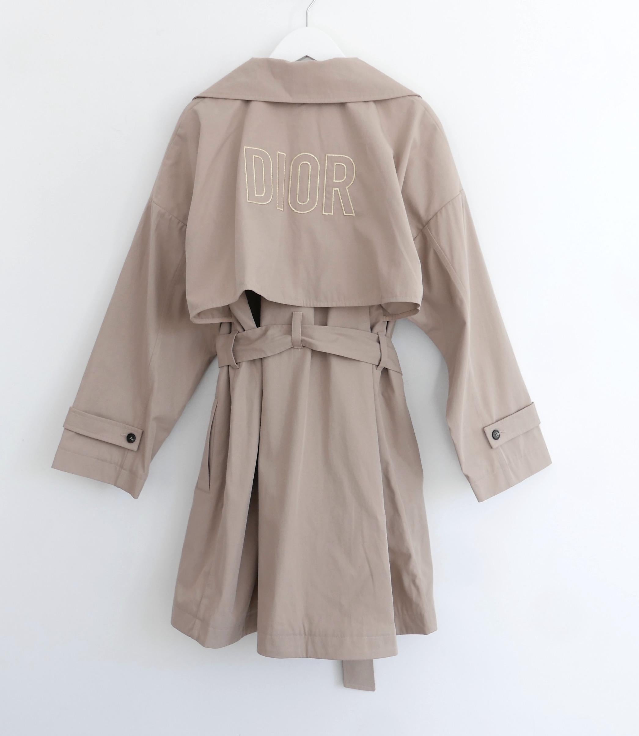 Exquisite Christian Dior girl’s trench coat.  Size 13A and will easily fit an adult too. 

Bought for £1850 and new with tags. 

Made from crisp, smooth shower proof dun coloured cotton with metallic gold embroidered  DIOR logo to back. It is
