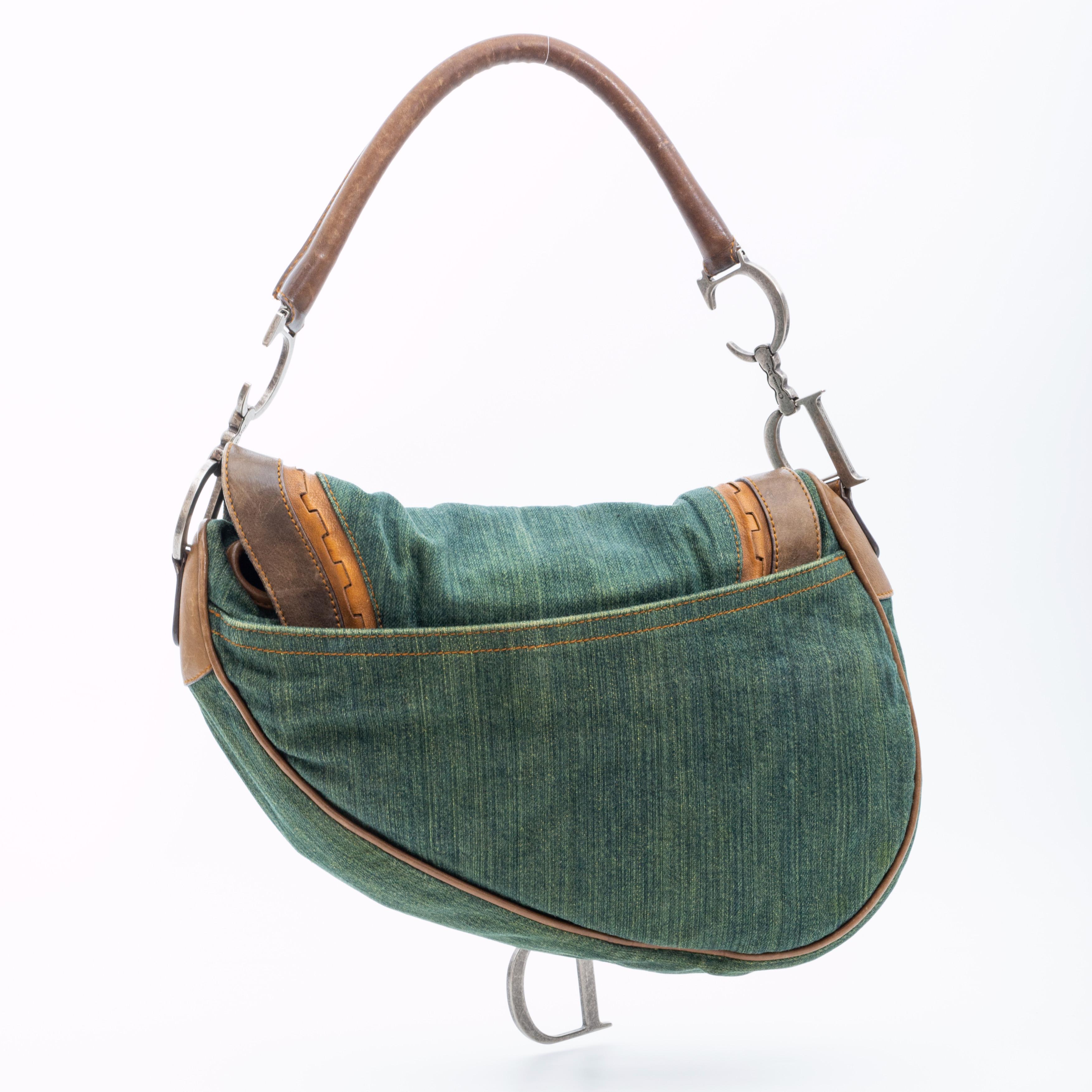 The bag is from 2006 and is made of supple washed green denim with aged calfskin trim and details. The bag features a fold over flap with a saddle shape, contrast stitching, antiqued silver metal hardware, monogram jacquard black fabric and an