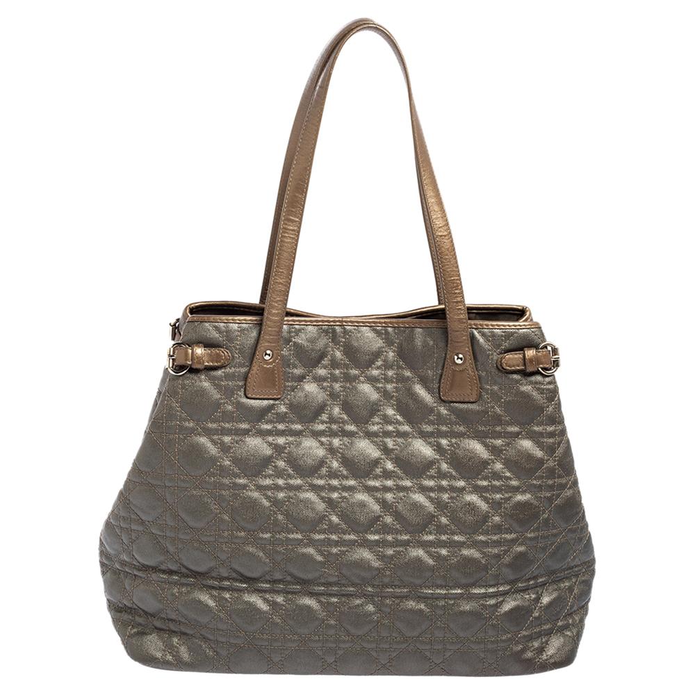 This popular Dior tote is a timeless piece. The bag comes in a Cannage canvas exterior with silver-tone hardware and Dior letter charms. It features double top handles and protective feet at the bottom. A buttoned closure opens to a nylon-lined